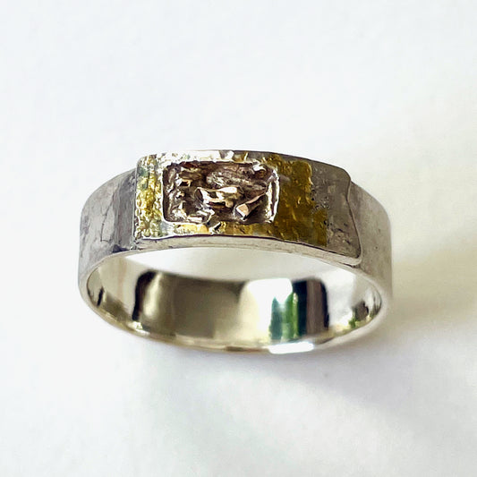 Inspired by the Dartmoor granite rocks abundant with large quartz crystals, megacrysts. 
The substantial Dartmoor Megacryst ring is made from recycled sterling silver and recycled 9ct gold. A hammered textured Matt finish on the outer surface and a high polish inside. 
The band is handcrafted from sold sterling recycled silver. The 'tor' (referring to the mounded rocks on the summit of hills on Dartmoor) is layered with a sterling silver 'tor', inlaid with recycled 9ct Gold.