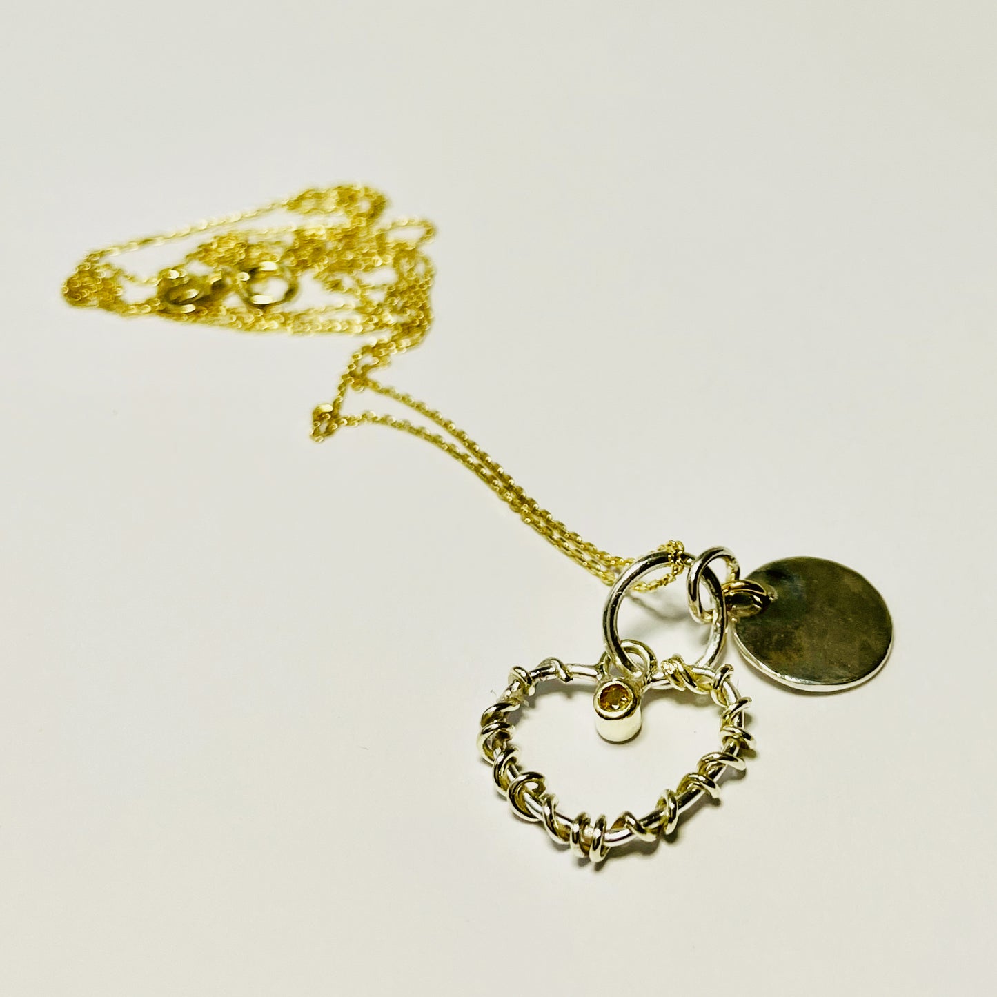 Expanded Skies Sapphire Yellow Heart Pendant has a beautiful ethically sourced Sri Lankan yellow faceted sapphire set in 9ct gold on a silver heart wound with 9ct gold accompanied by a small silver disk. Totally handcrafted on the edge of Dartmoor and made from high quality recycled sterling silver and recycled gold. Understated and beautiful, it can be worn every day or for special occasions.