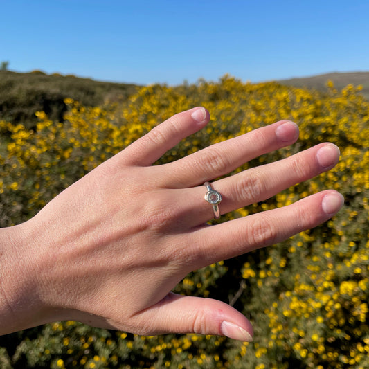 Haytor Quarry Pool White Sapphire Ring has a beautiful ethically sourced Sri Lankan faceted white 5mm sapphire, set in 9ct gold, on sterling silver band. Completely handcrafted from high quality recycled sterling silver and recycled gold. Understated and beautiful, it can be worn every day and for special occasions.
