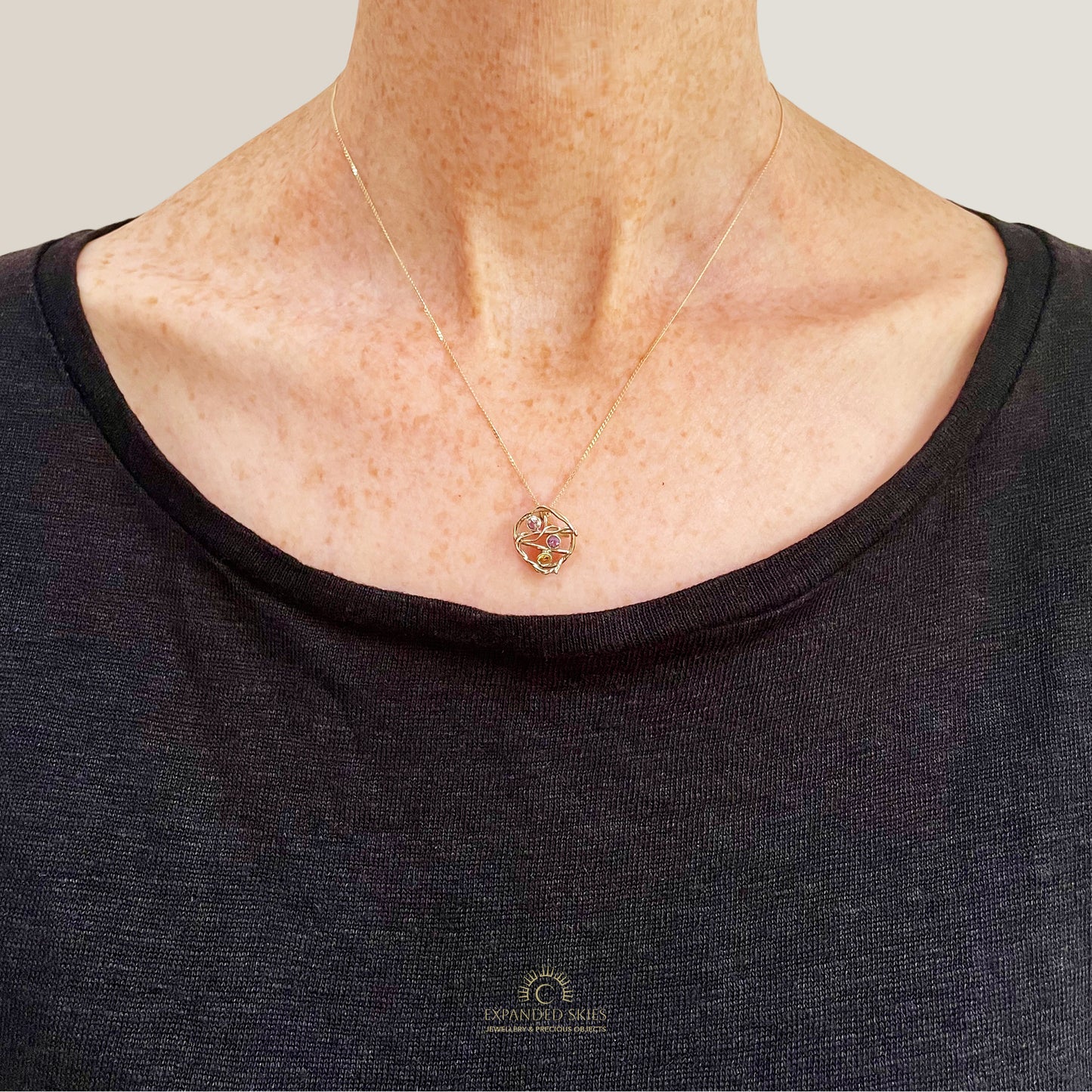 The Expanded Skies Haytor Heather and Gorse Amethyst and Sapphire Pendant evokes the beautiful yellows of the gorse and purples of the heather with an ethically sourced yellow sapphire and two amethysts held in twisting branches of 9ct yellow gold. The pendant comes with a 9ct gold chain, a choice of lengths are available, 16 inch chain pictured on person.