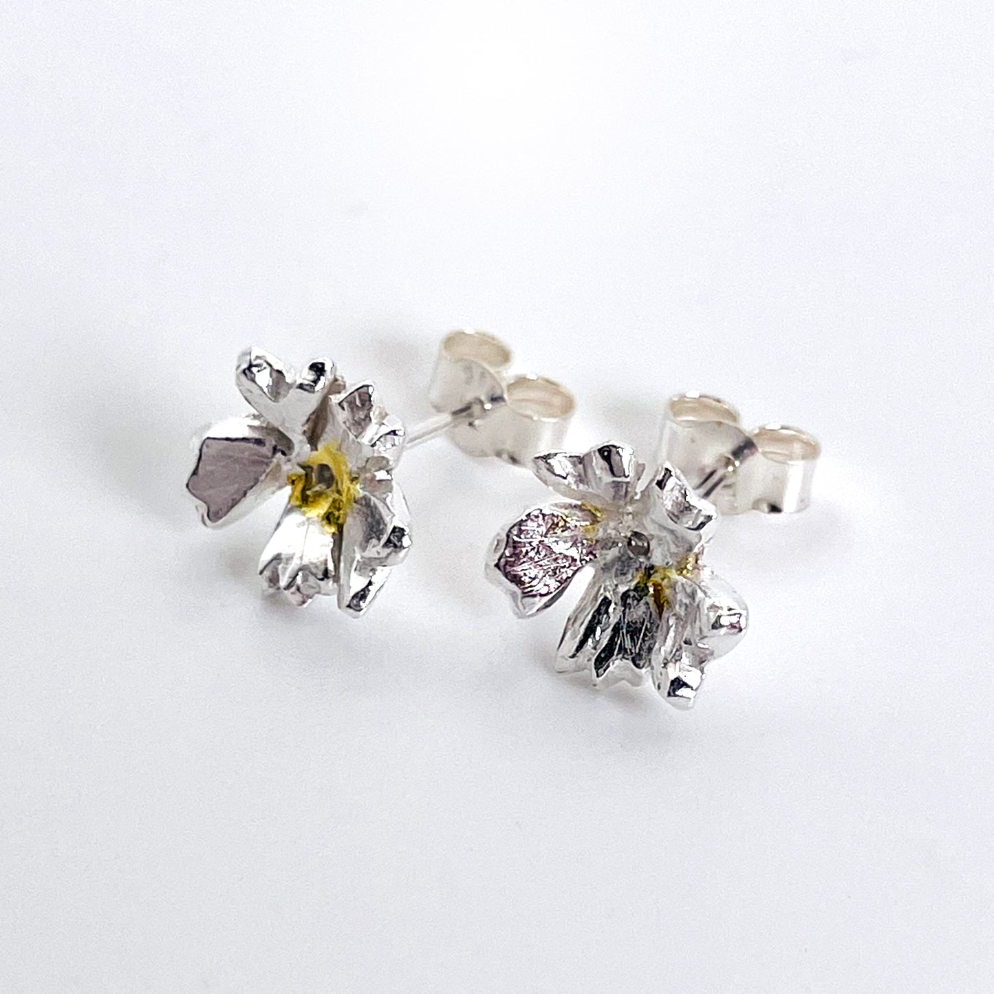 The Expanded Skies Dartmoor Field Rose Studs captures the joyous simple beauty of the field rose, Rosa arvensis, that is seen weaving brightly through the Dartmoor hedgerows and woodland.
Handcrafted in recycled fine silver with recycled 24ct gold accents and recycled sterling silver ear pins and scrolls.