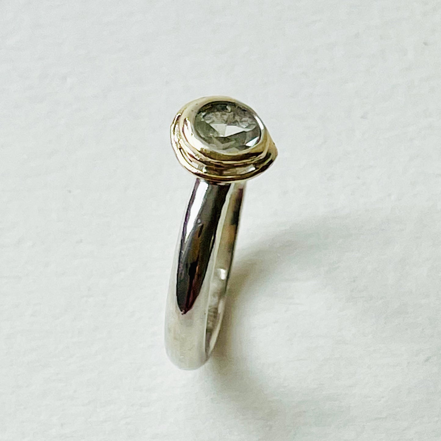 Haytor Quarry Pool White Sapphire Ring has a beautiful ethically sourced Sri Lankan faceted white 5mm sapphire, set in 9ct gold, on sterling silver band. Completely handcrafted from high quality recycled sterling silver and recycled gold. Understated and beautiful, it can be worn every day and for special occasions.
