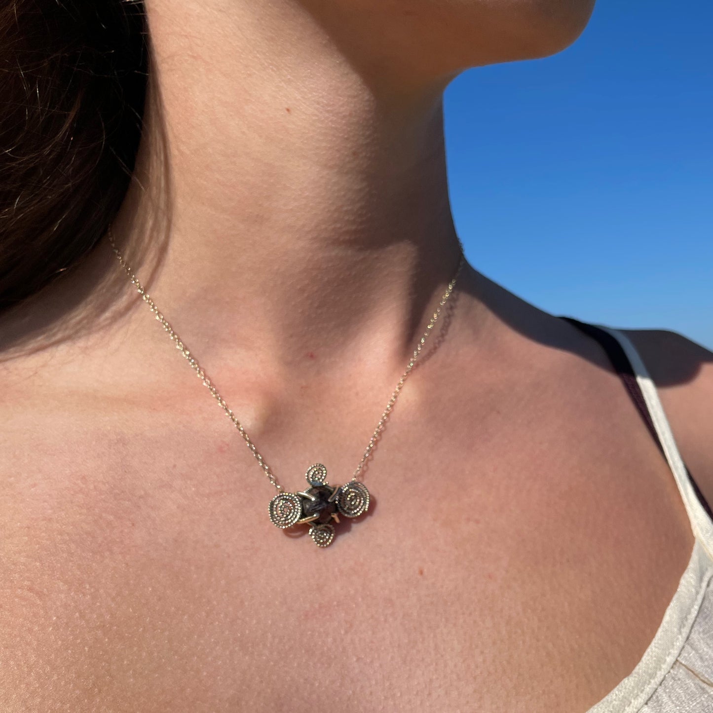 The Expanded Skies Raw Garnet Spiral Filigree Necklace has a beautiful raw Norwegian garnet set in 9ct gold. The garnet is set in a distinctive completely handcrafted 9ct gold filigree and claw setting. It features the neolithic symbol of the spiral, representing the life force and the cycles of life. This is a unique piece, one-of-a-kind. Handcrafted on the edge of Dartmoor and made from high quality recycled gold, Hallmarked by the London Assay Office.