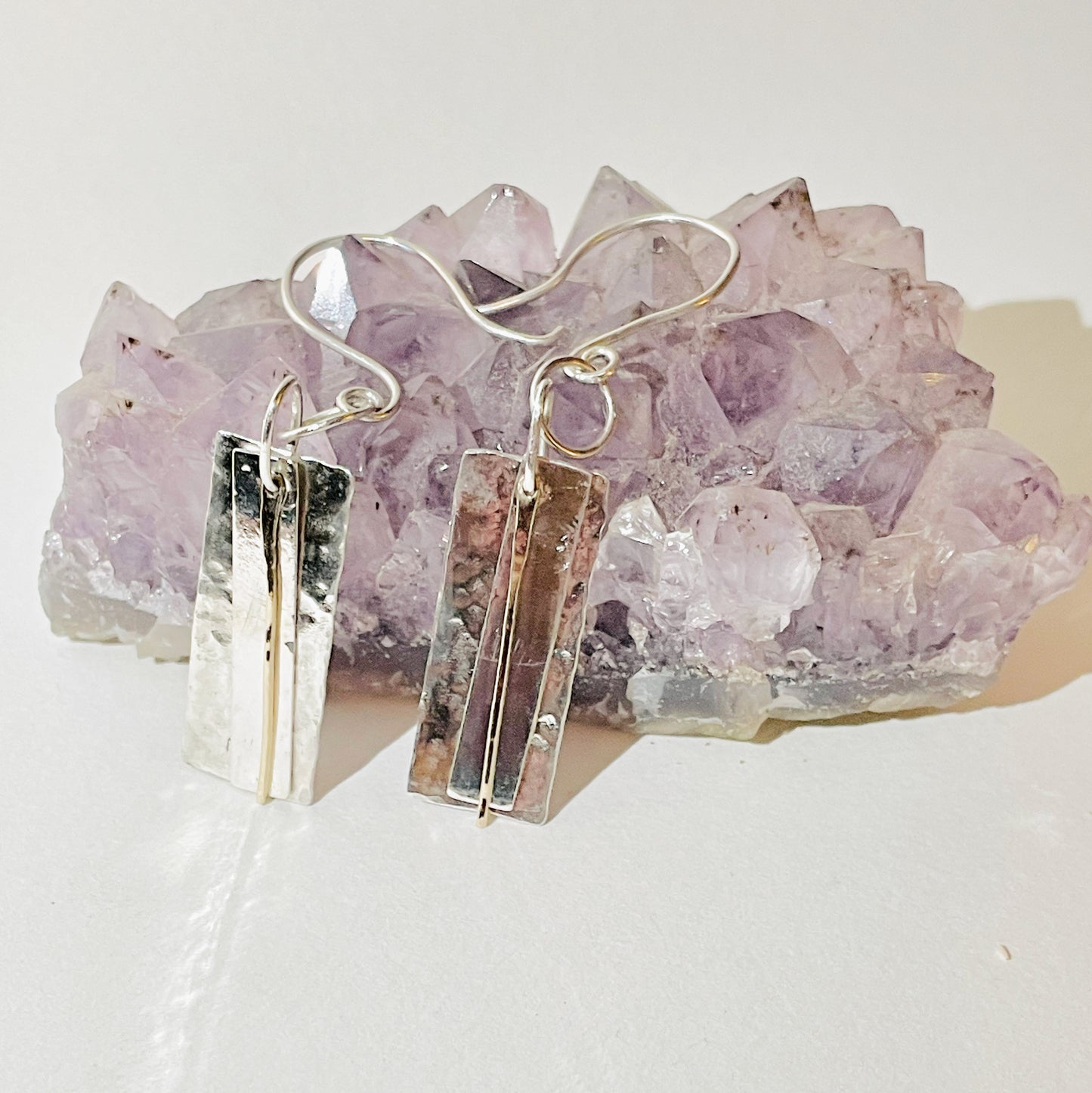 The Dartmoor Dart Valley earrings, are inspired by the River Dart, that viewed from high on top of granite moorland, glints and snakes through the steep sides of the deeply wooded valley. Handcrafted layers of solid recycled sterling silver are hammered and polished with a fine 9ct gold bar, that swing and catch the light.