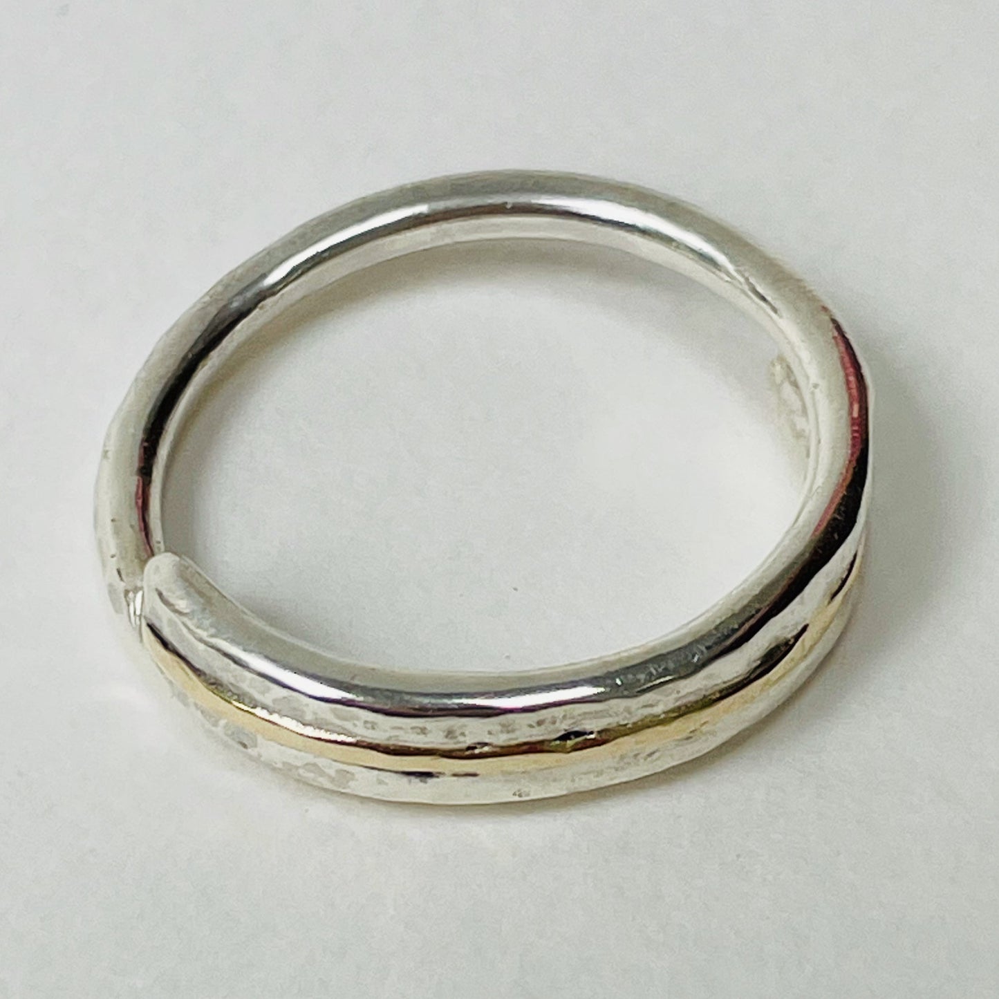 The Dartmoor Dart Valley Hammered Ring, inlaid with 9ct Gold, is inspired by the River Dart, that viewed from high on top of granite moorland, glints and snakes through the steep sides of the deeply wooded valley. The hammered band is handcrafted from a single band of sold sterling recycled silver at back that flows into a recycled 9ct gold band at the front, flanked by two silver bands. Wear everyday, perfect as a wedding ring or to accompany any outfit, understated, beautiful.