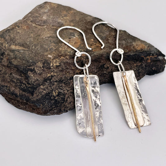 The Dartmoor Dart Valley earrings, are inspired by the River Dart, that viewed from high on top of granite moorland, glints and snakes through the steep sides of the deeply wooded valley.  Handcrafted layers of solid recycled sterling silver are hammered and polished with a fine 9ct gold bar, that swing and catch the light.