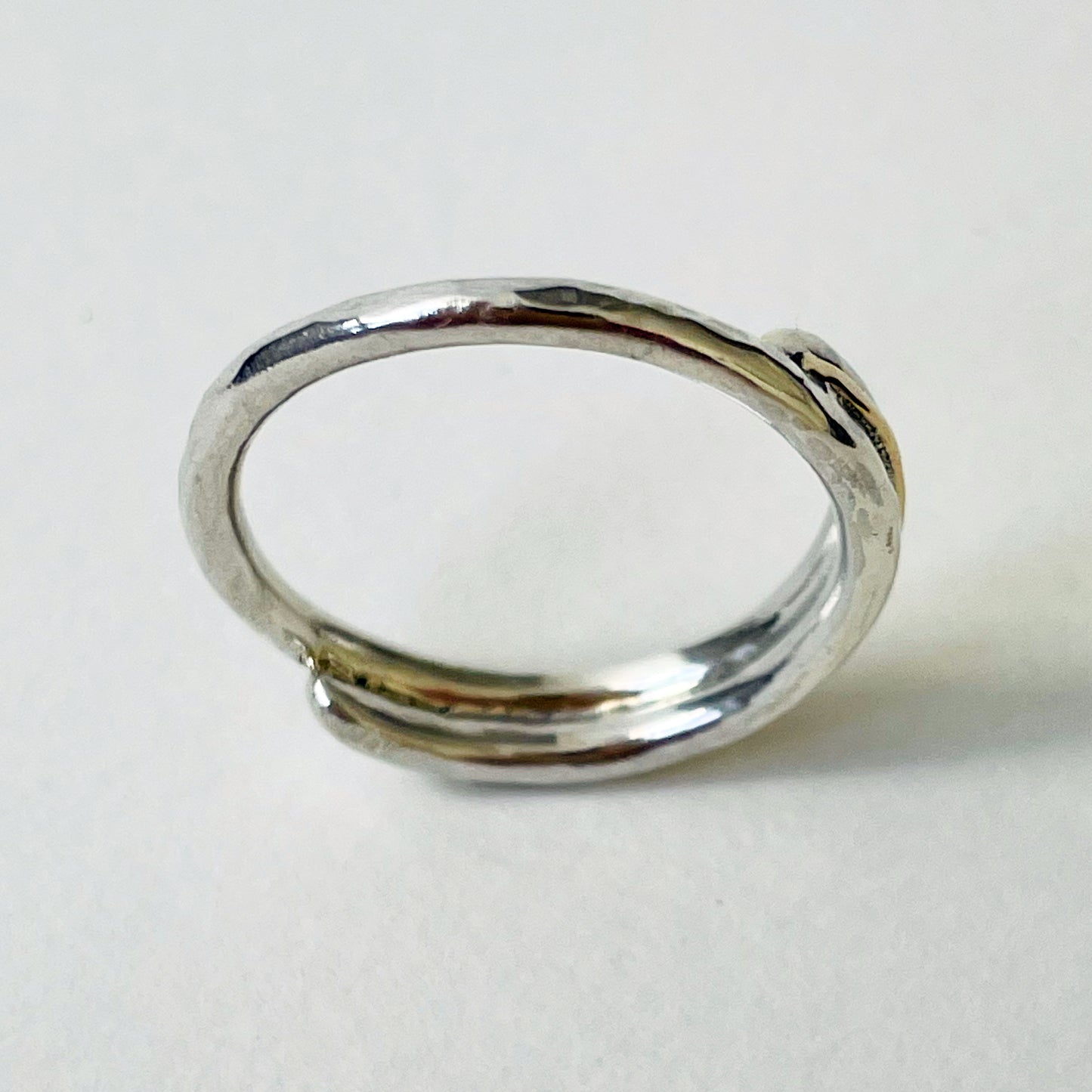 The Dartmoor Dart Valley Hammered Ring, inlaid with 9ct Gold, is inspired by the River Dart, that viewed from high on top of granite moorland, glints and snakes through the steep sides of the deeply wooded valley. The hammered band is handcrafted from a single band of sold sterling recycled silver at back that flows into a recycled 9ct gold band at the front, flanked by two silver bands. Wear everyday, perfect as a wedding ring or to accompany any outfit, understated, beautiful.