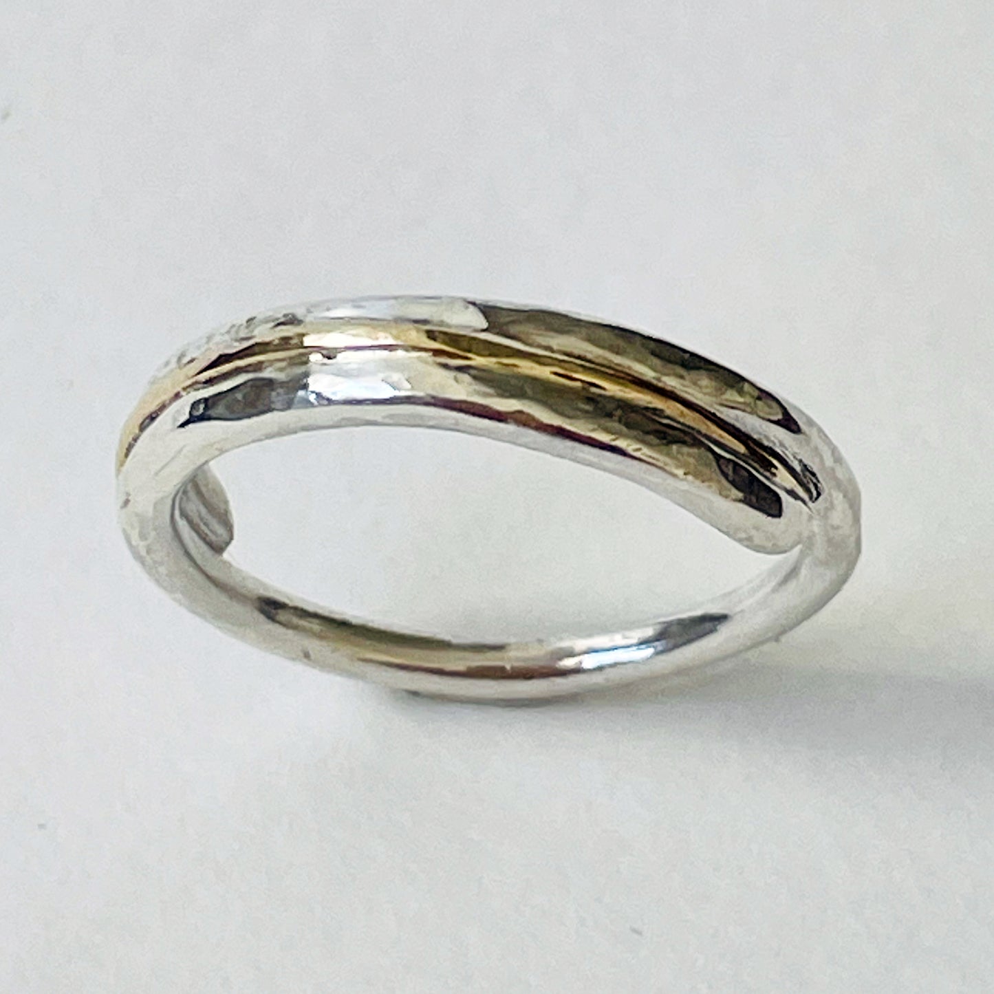 The Dartmoor Dart Valley Hammered Ring, inlaid with 9ct Gold, is inspired by the River Dart, that viewed from high on top of granite moorland, glints and snakes through the steep sides of the deeply wooded valley. The hammered band is handcrafted from a single band of sold sterling recycled silver at back that flows into a recycled 9ct gold band at the front, flanked by two silver bands. Wear everyday, perfect as a wedding ring or to accompany any outfit, understated, beautiful.