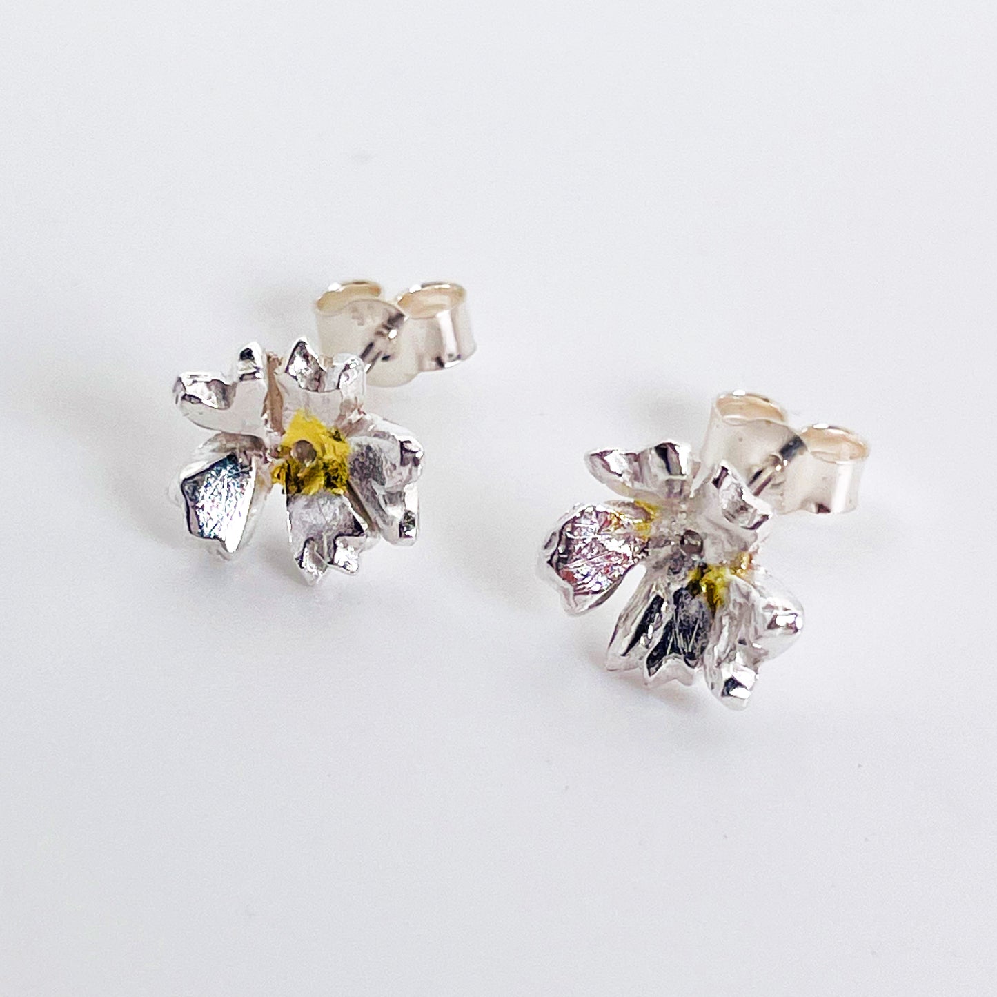 The Expanded Skies Dartmoor Field Rose Studs captures the joyous simple beauty of the field rose, Rosa arvensis, that is seen weaving brightly through the Dartmoor hedgerows and woodland.
Handcrafted in recycled fine silver with recycled 24ct gold accents and recycled sterling silver ear pins and scrolls.