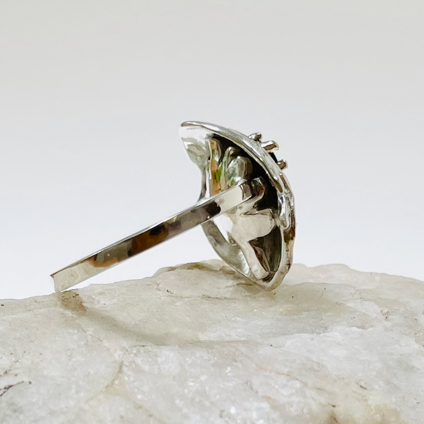 he Hembury Castle Ring design is based on archaeological remains of the mott and bailey Norman castle in Hembury Woods, on the edge of Dartmoor. It is created with hand engraving, inlaid with 9ct gold and set with a beautiful 3mm brilliant cut green Australian sapphire, ethically sourced from Nineteen48. The 'secret' underside of the ring has the symbol of for non-coniferous woodland.