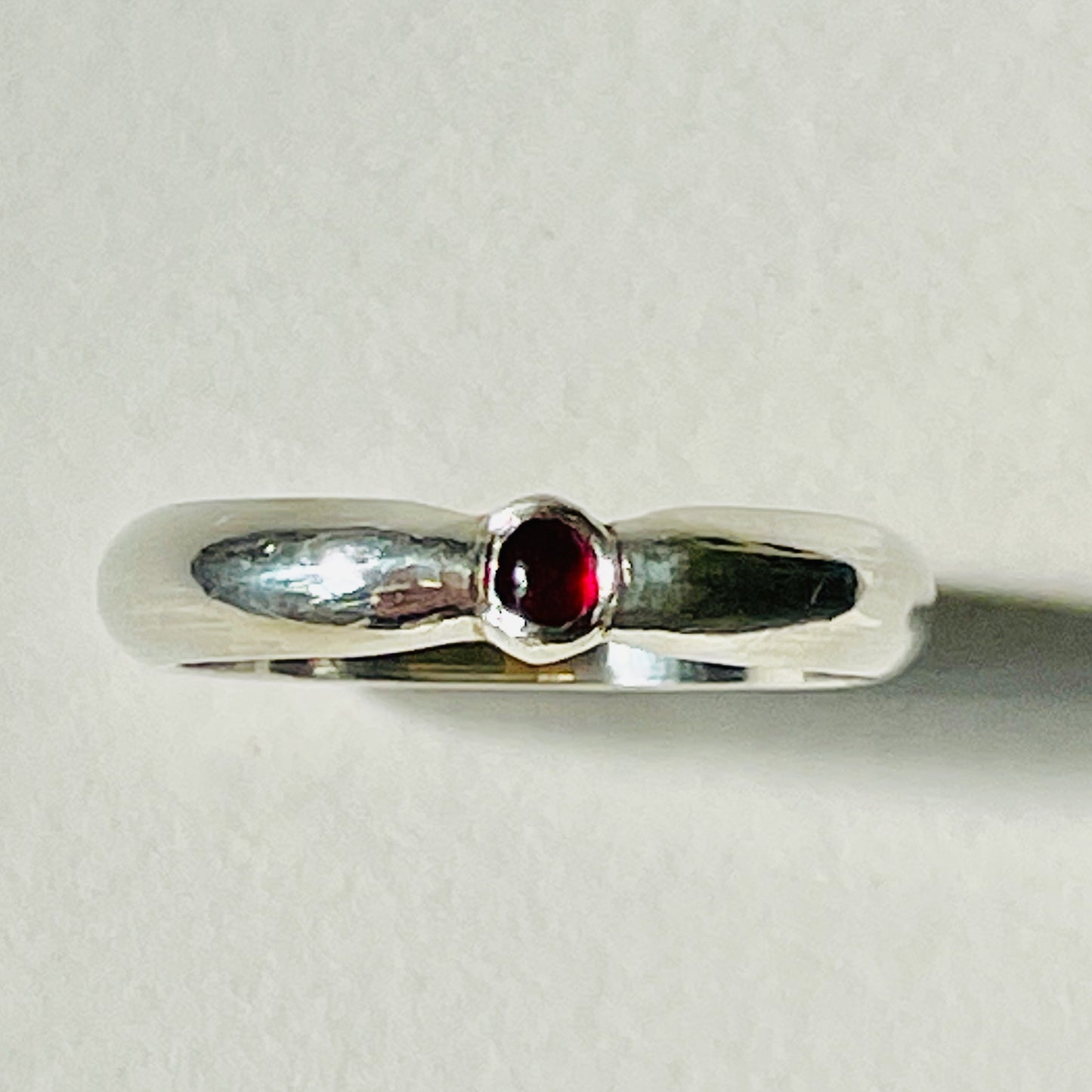 The Ruby-Joy Ring is has a hint of the 1950's exuberance of pinched waists and wide skirts, with a tapering silver band that clasps the oval lustrous pink-red ethically sourced Greenland ruby. With a timeless elegance that can be worn everyday or for special occasions. Dimensions: 2mm D-shaped recycled sterling silver band 4mm x 3mm approx Ethically Mined Greenland Ruby