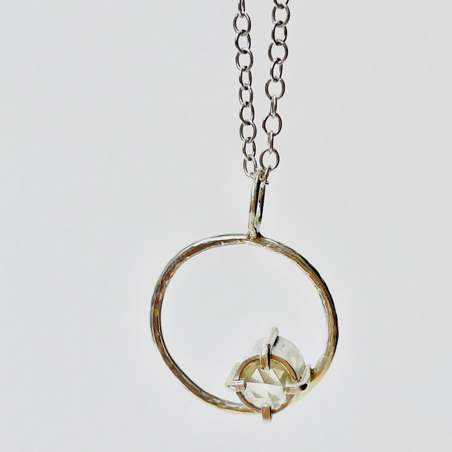 The Moon Light White Sapphire pendant sparkles as its facets reflects the light. The beautiful 5mm rose cut ethically mined Sri Lankan white sapphire has a handcrafted four claw setting on a hammered silver sterling silver band. Understated and beautiful, it can be worn everyday or for special occasions. The pendant comes with a 1.7mm recycled sterling silver trace chain
