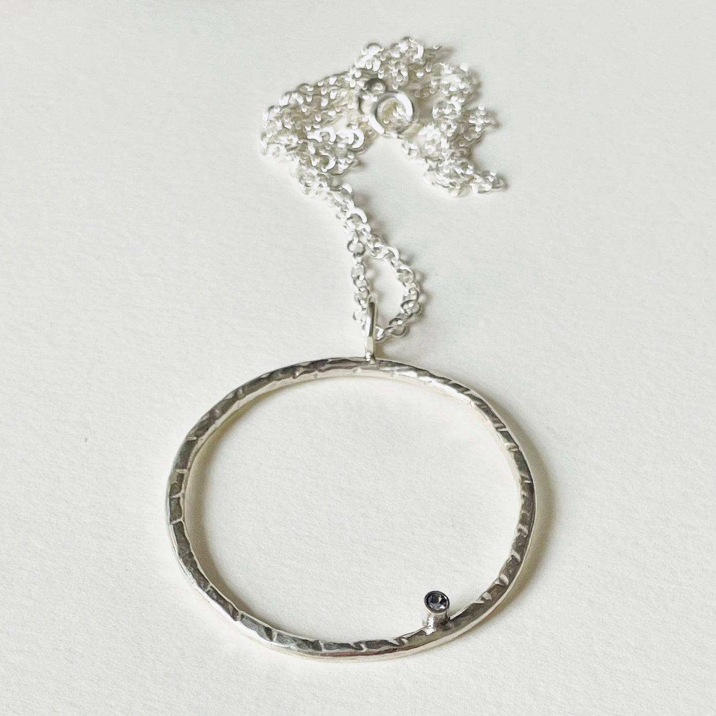 Moonbeam White Sapphire Pendant is totally handcrafted. The delicate 2mm ethically mined, Sri Lankan white sapphire is set on a hammered silver sterling silver band, made from high quality recycled sterling silver. Understated and beautiful, it can be worn everyday or for special occasions.