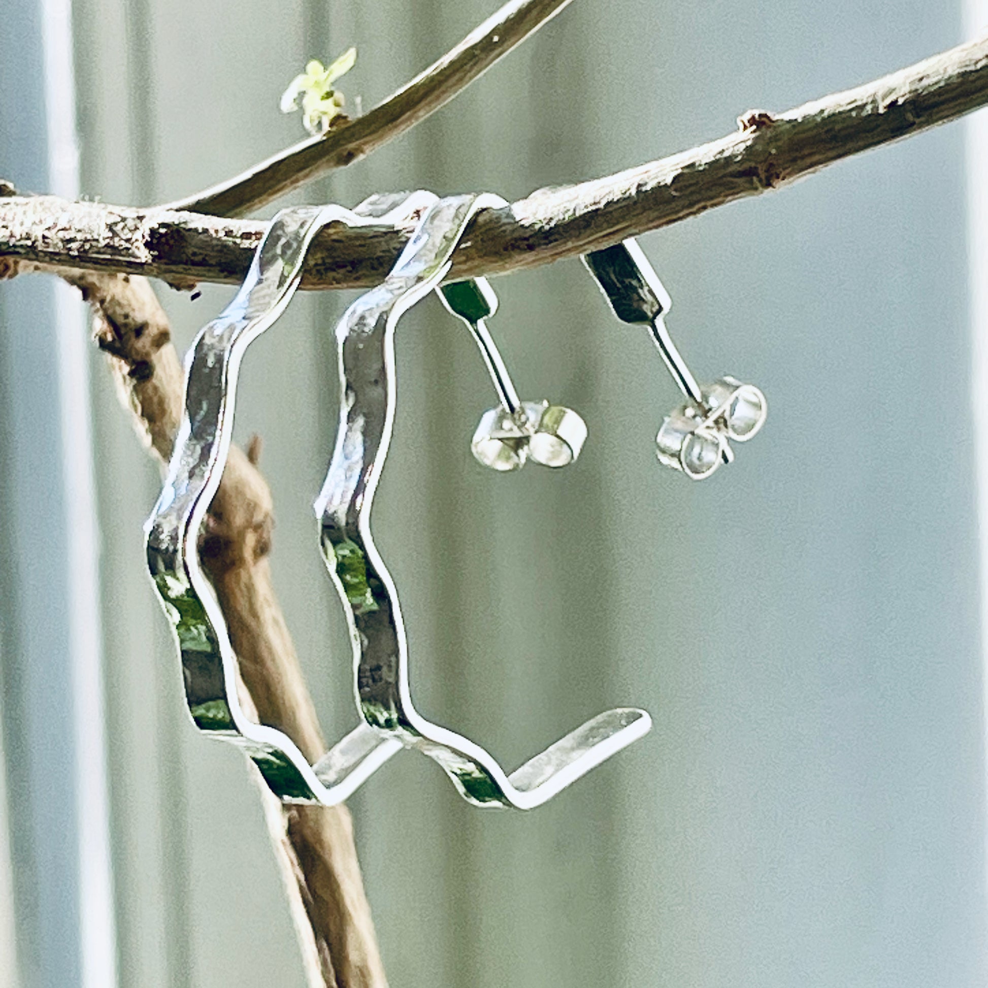 Inspired by the River Dart viewed from high on top of granite moorland, glints and snakes through the steep sides of the deeply wooded valley. The Expanded Skies, River Dart Wavy Hoop Earrings are handcrafted from solid recycled sterling silver with recycled sterling silver pins and scroll backs. Simple and elegant, with a hammered finish they can be worn everyday for any occasion.