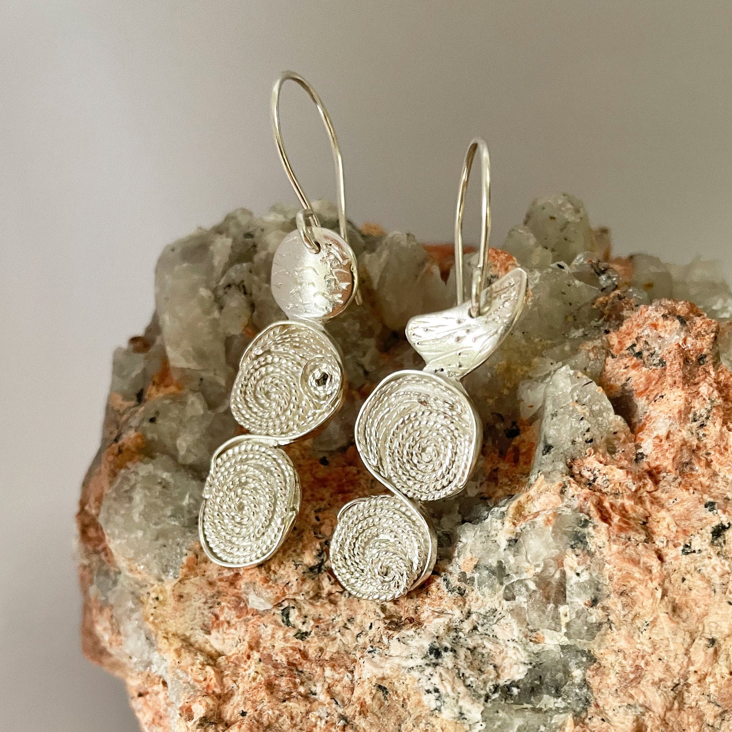 The River Dart Filigree Earrings are inspired by the River Dart that eddy around rocks, turning the flow into tiny whirlpools.
Handcrafted fine silver filigree is made with very fine silver wires are twisted to make a rope, that is sculpted and mounted onto hand engraved sterling silver. The earrings have sterling silver ear wires. Eye catching and completely unique, they are one-of-a-kind.