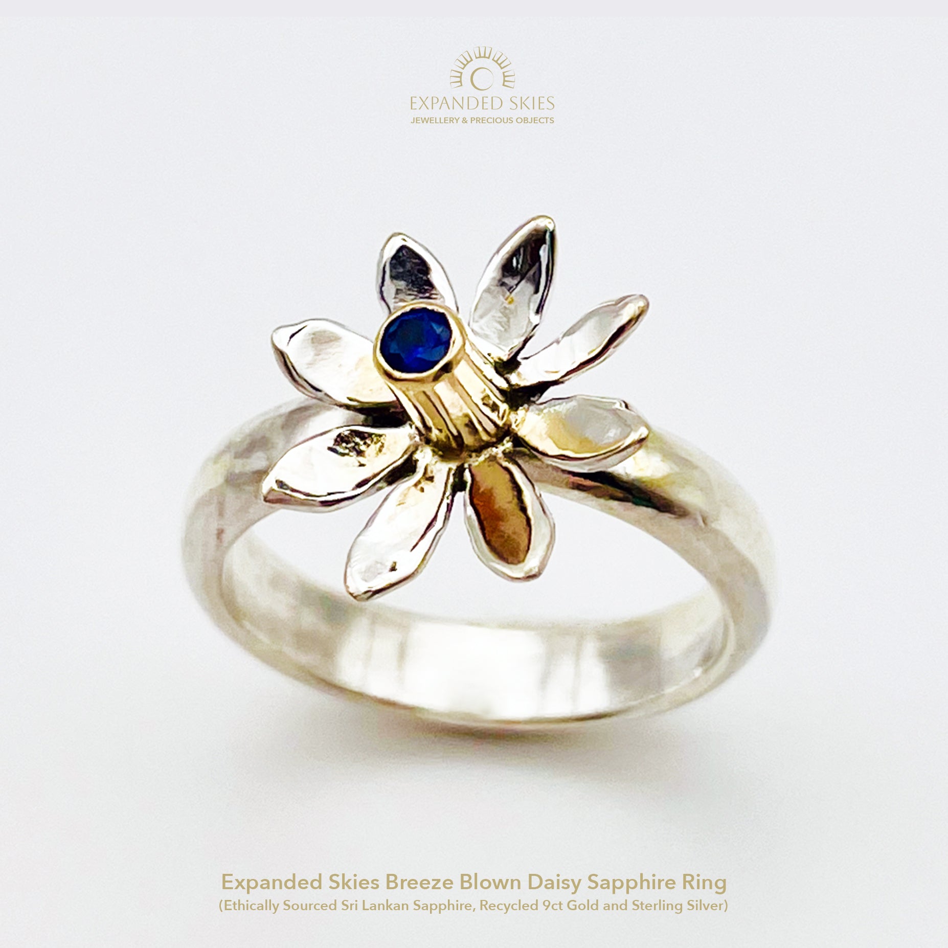 The Expanded Skies Breeze Blown Daisy Sapphire Ring is joyful! A beautiful brilliant bright blue, ethically sourced, Sri Lankan sapphire is set in solid 9ct gold that reflects onto to the high polish recycled silver petals, giving a sense of movement. The ring is totally handcrafted on the edge of Dartmoor.