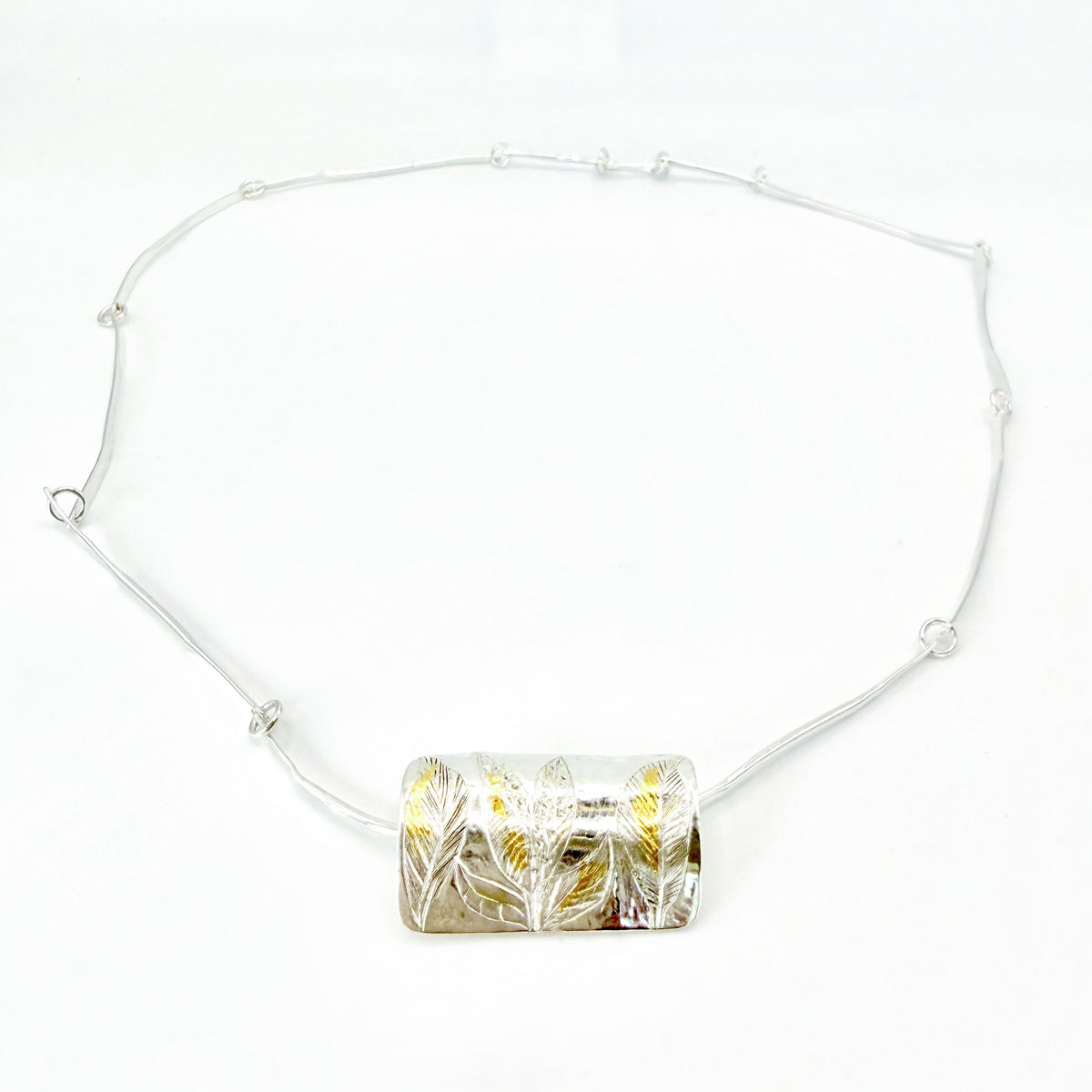 The Expanded Skies Dartmoor Wild Honeysuckle Leaves Necklace is a hand engraved of the graceful honeysuckle (Lonicera periclymenum) as it winds through the trees and brambles in Ausewell Woods. Handcrafted in fine silver with 24ct gold accents, with a completely handcrafted stem and tendril chain in sterling silver. Simple and elegant with a polished finish, it can be worn everyday for any occasion.