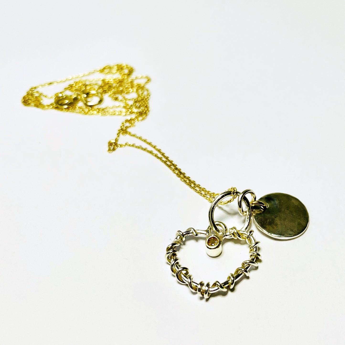 Expanded Skies Sapphire Yellow Heart Pendant has a beautiful ethically sourced Sri Lankan yellow faceted sapphire set in 9ct gold on a silver heart wound with 9ct gold accompanied by a small silver disk. Totally handcrafted on the edge of Dartmoor and made from high quality recycled sterling silver and recycled gold. Understated and beautiful, it can be worn every day or for special occasions.