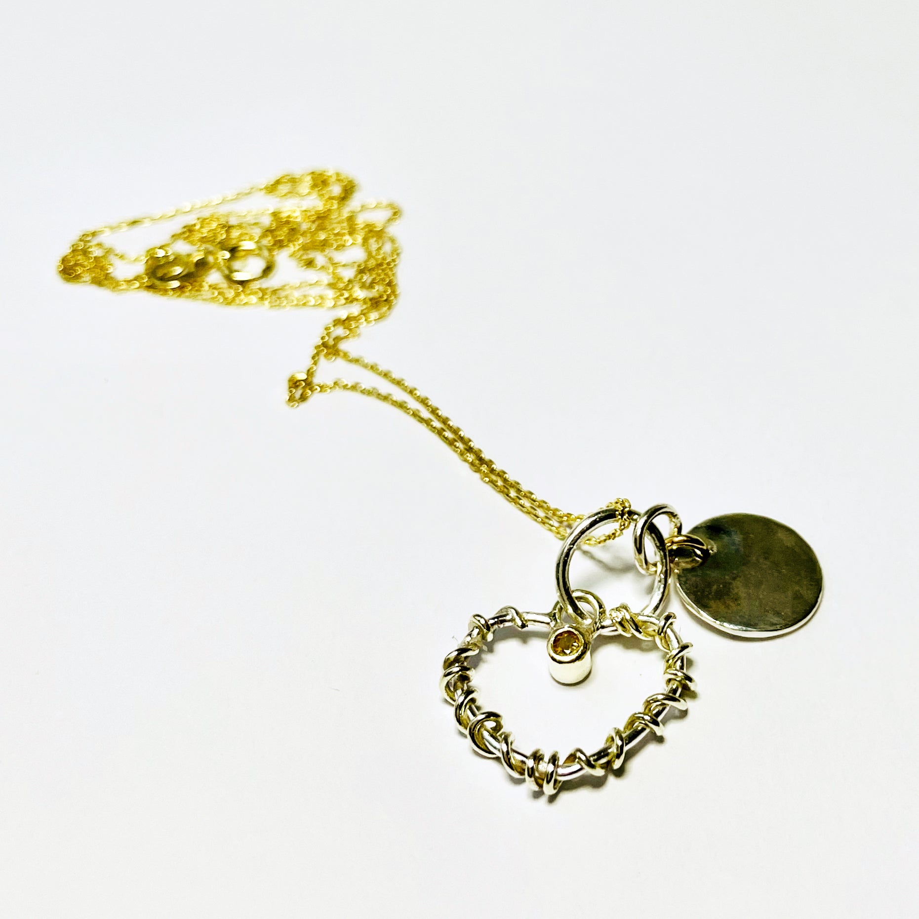 Expanded Skies Sapphire Yellow Heart Pendant has a beautiful ethically sourced Sri Lankan yellow faceted sapphire set in 9ct gold on a silver heart wound with 9ct gold accompanied by a small silver disk. Totally handcrafted on the edge of Dartmoor and made from high quality recycled sterling silver and recycled gold. Understated and beautiful, it can be worn every day or for special occasions.