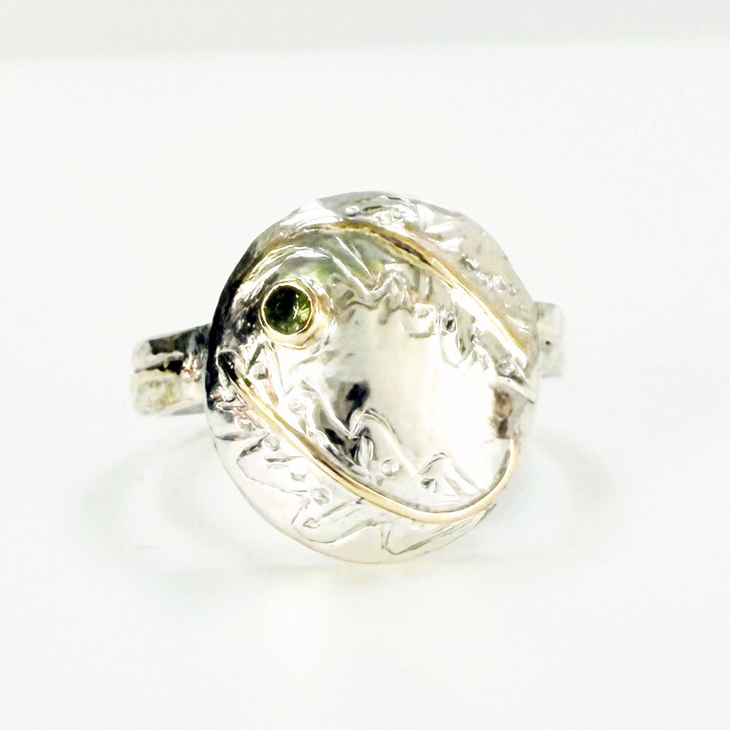 Expanded Skies Two Dartmoor Oak Leaves Sapphire Ring is inspired by the beautiful oak seedlings in Hembury Woods created in recycled sterling and fine silver, inlaid with 9ct gold with an ethically sourced Australian green sapphire set in 9ct gold, with hand engraved oak leaves.