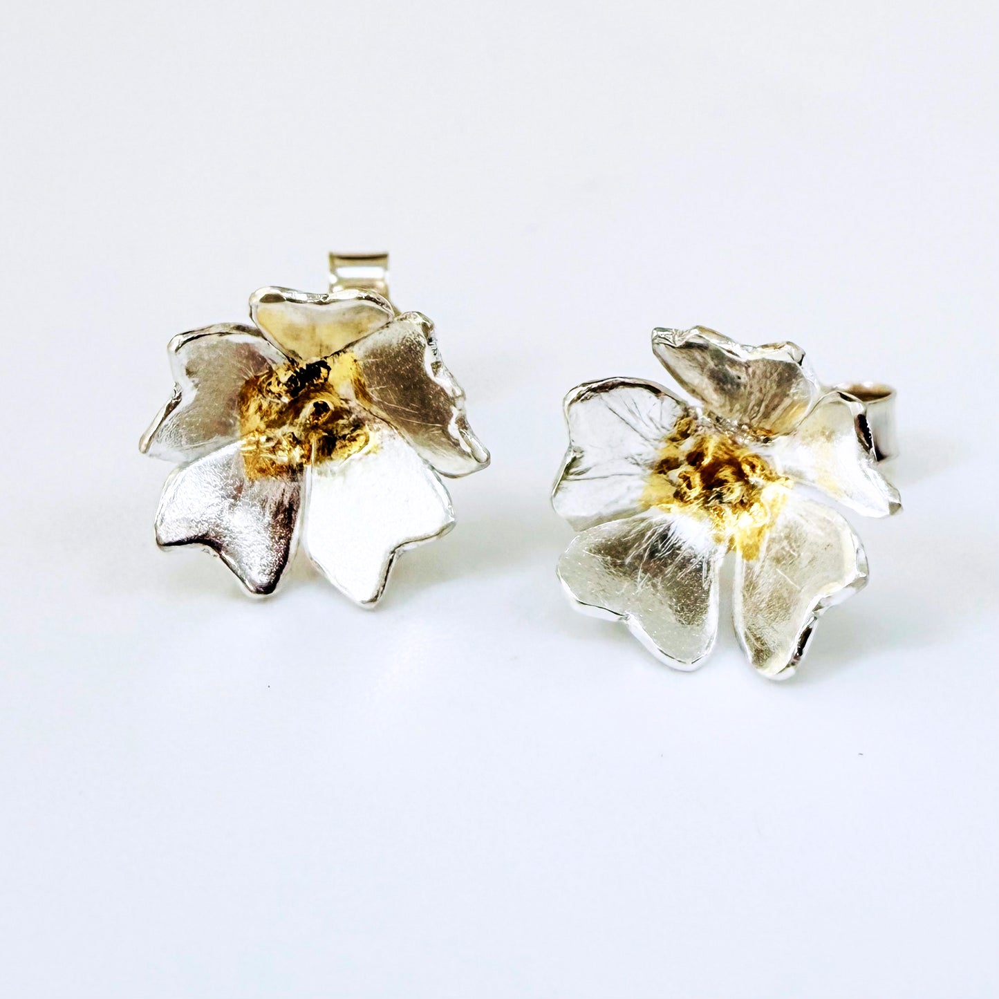 The Expanded Skies Dartmoor Field Rose Studs captures the joyous simple beauty of the field rose, Rosa arvensis, that is seen weaving brightly through the Dartmoor hedgerows and woodland.
Handcrafted in recycled fine silver with recycled 24ct gold accents and recycled sterling silver ear pins and scrolls.