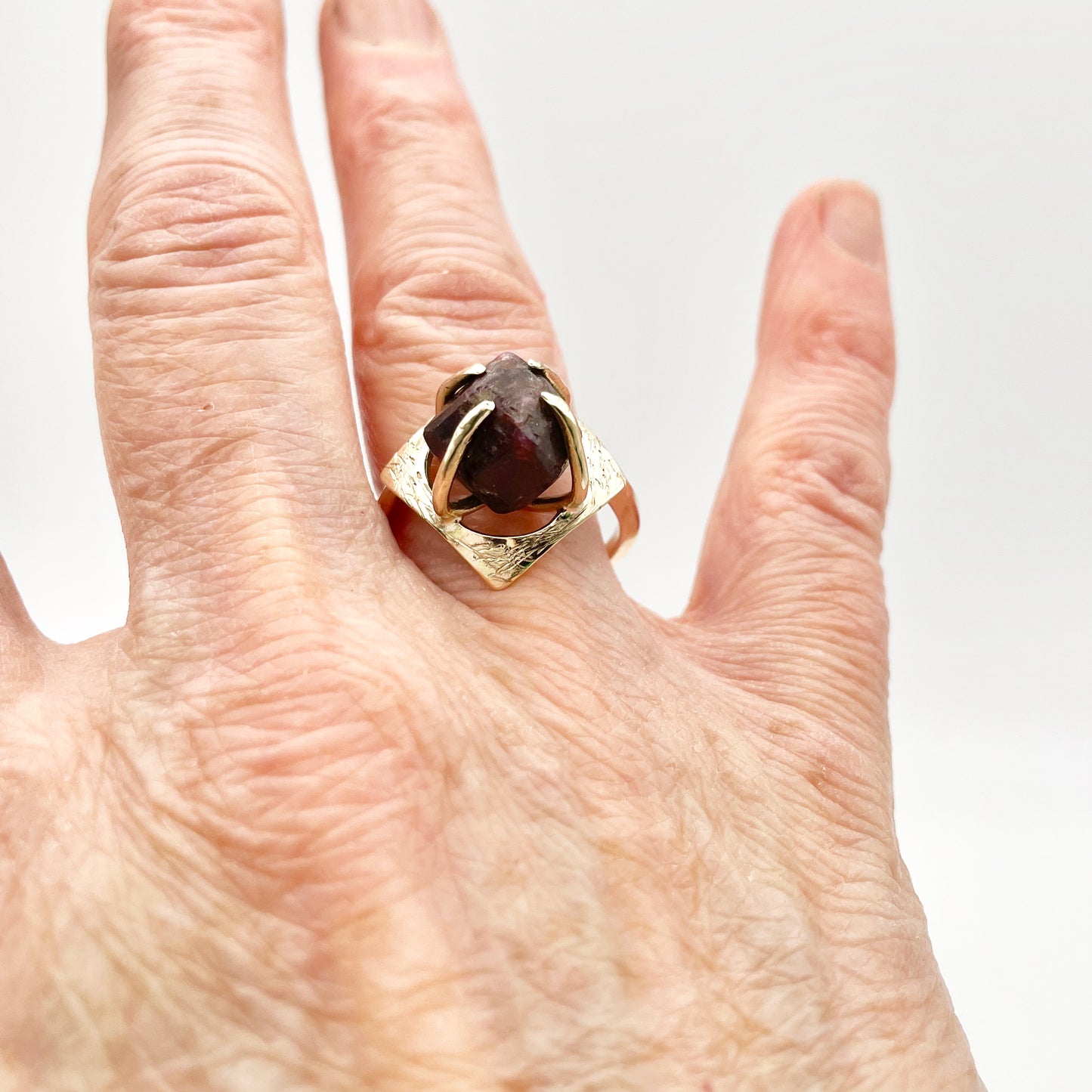 The Expanded Skies Heaven and Earth Raw Garnet Ring has a beautiful raw Norwegian garnet set in 9ct gold. The garnet is set in a distinctive completely handcrafted engraved claw setting. This is a unique piece, one-of-a-kind. Handcrafted on the edge of Dartmoor and made from high quality recycled gold, Hallmarked by the London Assay Office.