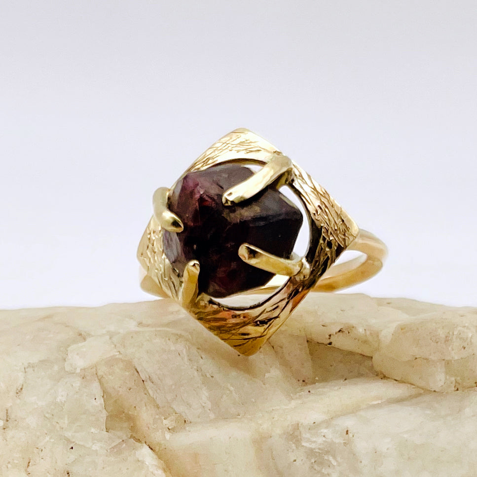 The Expanded Skies Heaven and Earth Raw Garnet Ring has a beautiful raw Norwegian garnet set in 9ct gold. The garnet is set in a distinctive completely handcrafted engraved claw setting. This is a unique piece, one-of-a-kind. Handcrafted on the edge of Dartmoor and made from high quality recycled gold, Hallmarked by the London Assay Office.