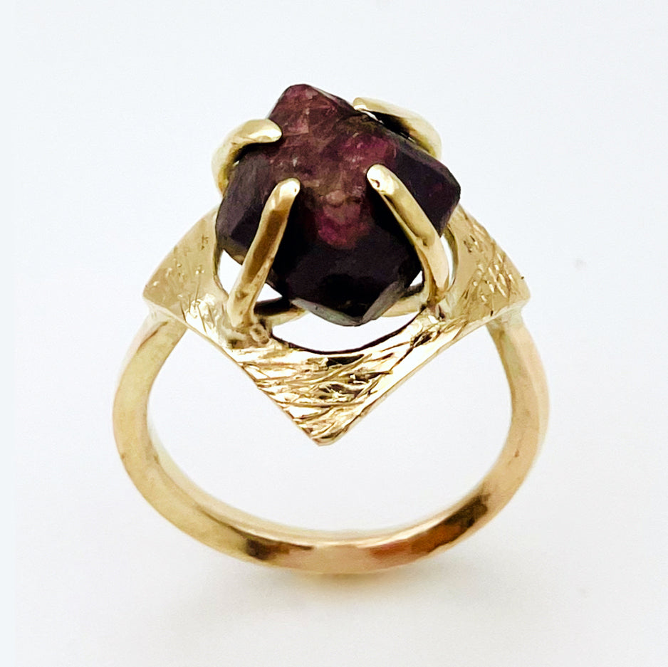 The Expanded Skies Heaven and Earth Raw Garnet Ring has a beautiful raw Norwegian garnet set in 9ct gold. The garnet is set in a distinctive completely handcrafted engraved claw setting. This is a unique piece, one-of-a-kind. Handcrafted on the edge of Dartmoor and made from high quality recycled gold, Hallmarked by the London Assay Office.