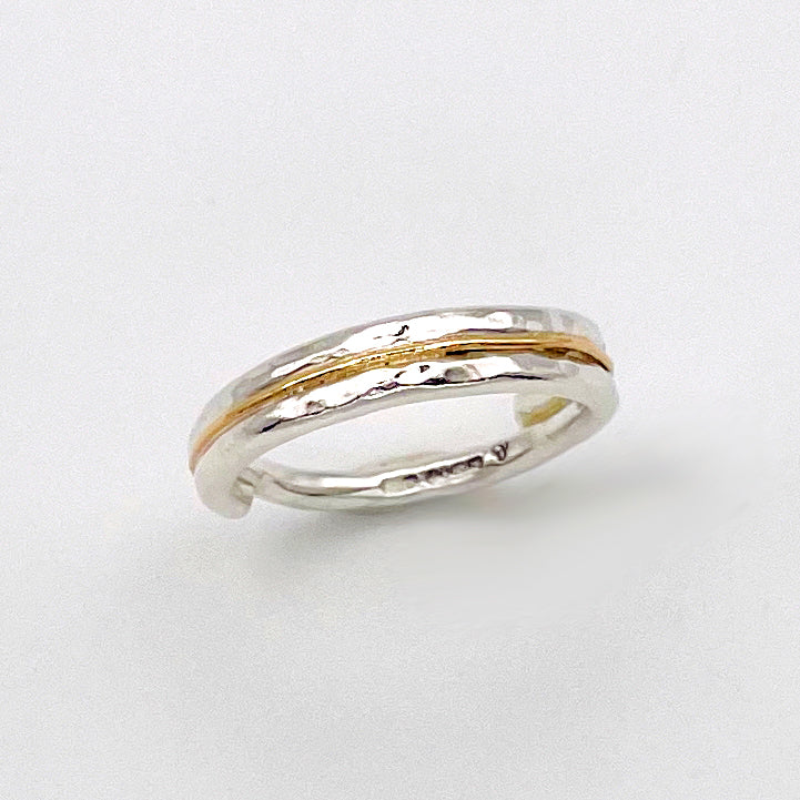 The Expanded Skies Dartmoor Dart Valley Hammered Ring, inlaid with 9ct Gold, is inspired by the River Dart, that viewed from high on top of granite moorland, glints and snakes through the steep sides of the deeply wooded valley. The hammered band is handcrafted from a single band of sold sterling recycled silver at back that flows into a recycled 9ct gold band at the front, flanked by two silver bands.