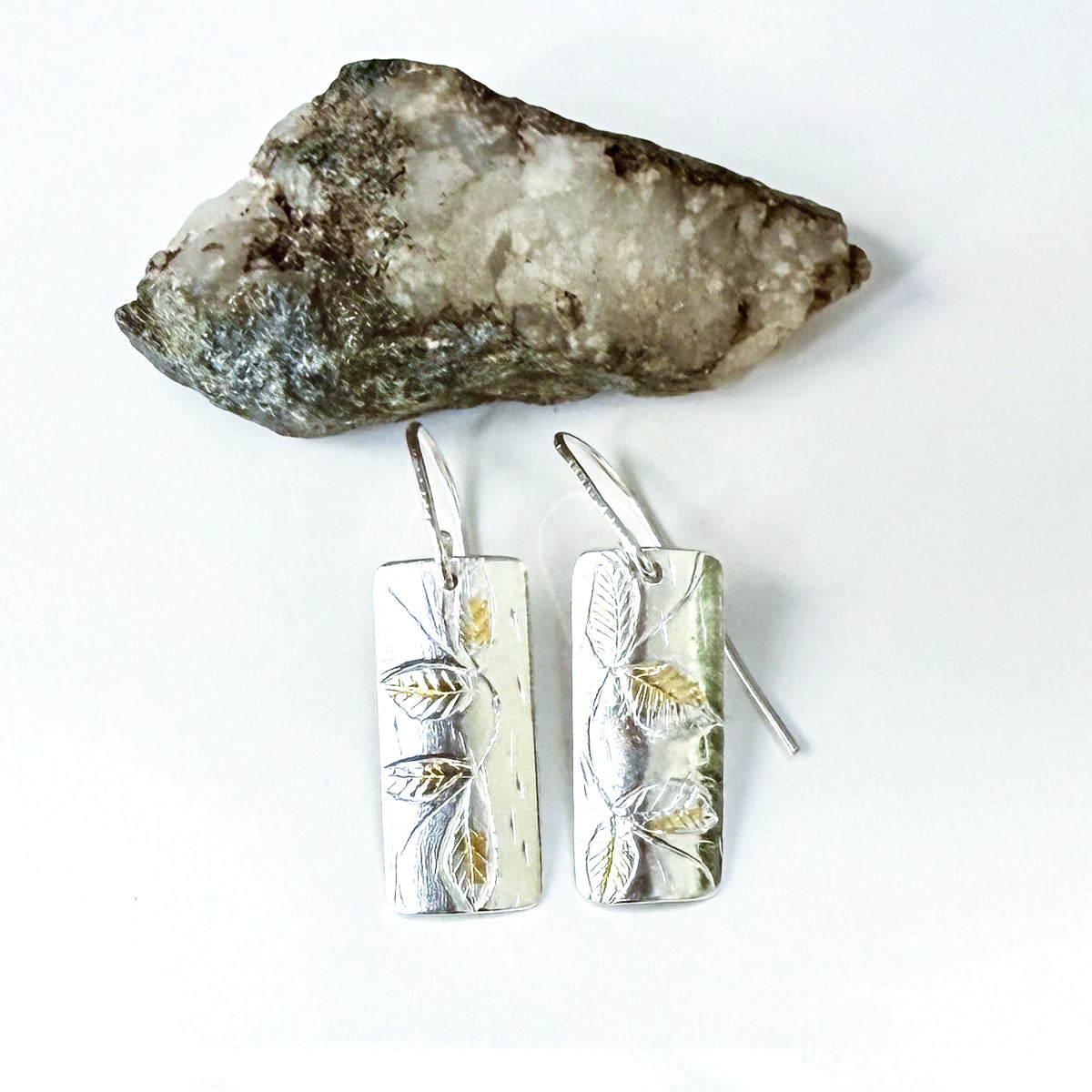 The Expanded Skies Dartmoor Honeysuckle Leaves Drop Earrings are hand engravings of the graceful honeysuckle (Lonicera periclymenum) as it winds through the trees and brambles in Ausewell Woods.

Handcrafted in recycled fine silver with recycled 24ct gold accents with sterling silver ear wires. Each earring’s hand engraving is unique. Simple and elegant with a textured, polished finish, they can be worn everyday for any occasion.

The earrings are totally handcrafted on the edge of Dartmoor and made from hi