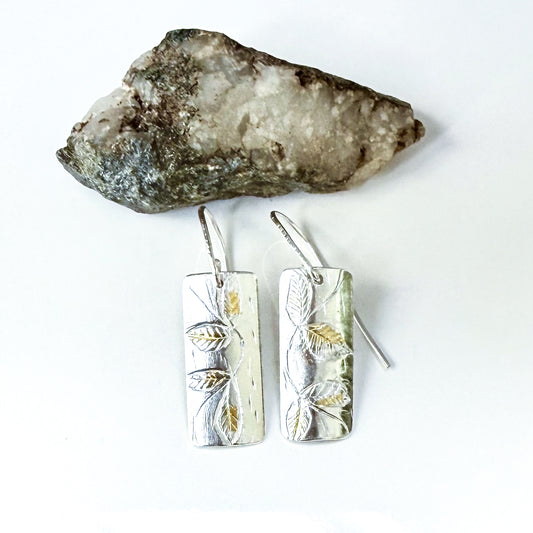 The Expanded Skies Dartmoor Honeysuckle Leaves Drop Earrings are hand engravings of the graceful honeysuckle (Lonicera periclymenum) as it winds through the trees and brambles in Ausewell Woods.

Handcrafted in recycled fine silver with recycled 24ct gold accents with sterling silver ear wires. Each earring’s hand engraving is unique. Simple and elegant with a textured, polished finish, they can be worn everyday for any occasion.

The earrings are totally handcrafted on the edge of Dartmoor and made from hi