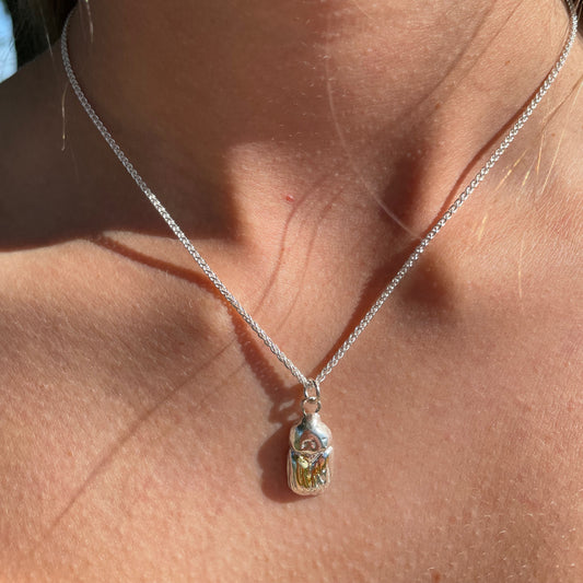 The Expanded Skies Dartmoor Scarab Pendant Necklace is inspired by the Dumbledore or Dor beetle, recycled fine silver with 24ct gold accents, worn on Dartmoor.