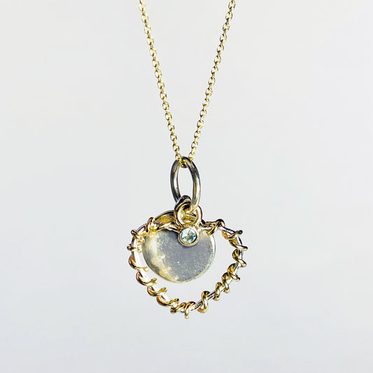 Expanded Skies Sapphire Sky Blue Heart Pendant has a beautiful ethically sourced Sri Lankan mid blue faceted sapphire set in 9ct gold on a silver heart wound with 9ct gold accompanied by a small silver disk. Totally handcrafted on the edge of Dartmoor and made from high quality recycled sterling silver and recycled gold. 