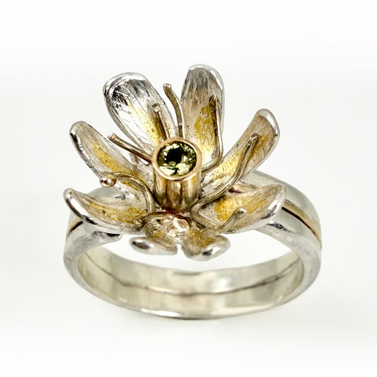 Expanded Skies Dartmoor Celandine Sapphire Ring celebrates the beauty of the waysides and meadows, radiant with wild yellow celandines (Ficaria verna).

The ring is totally handcrafted on the edge of Dartmoor. The band is made from sterling silver, inlaid on the shoulders with 9ct gold.

The flower is made from fine silver with 24ct gold accents fused to the surface of the petals. The celandine has a 9ct gold setting for the beautiful ethically sourced yellow-green sapphire, that really captures the colours
