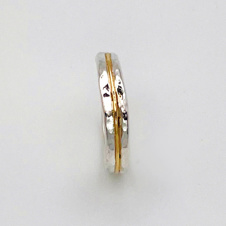 The Expanded Skies Dartmoor Dart Valley Hammered Ring, inlaid with 9ct Gold, is inspired by the River Dart, that viewed from high on top of granite moorland, glints and snakes through the steep sides of the deeply wooded valley. The hammered band is handcrafted from a single band of sold sterling recycled silver at back that flows into a recycled 9ct gold band at the front, flanked by two silver bands.