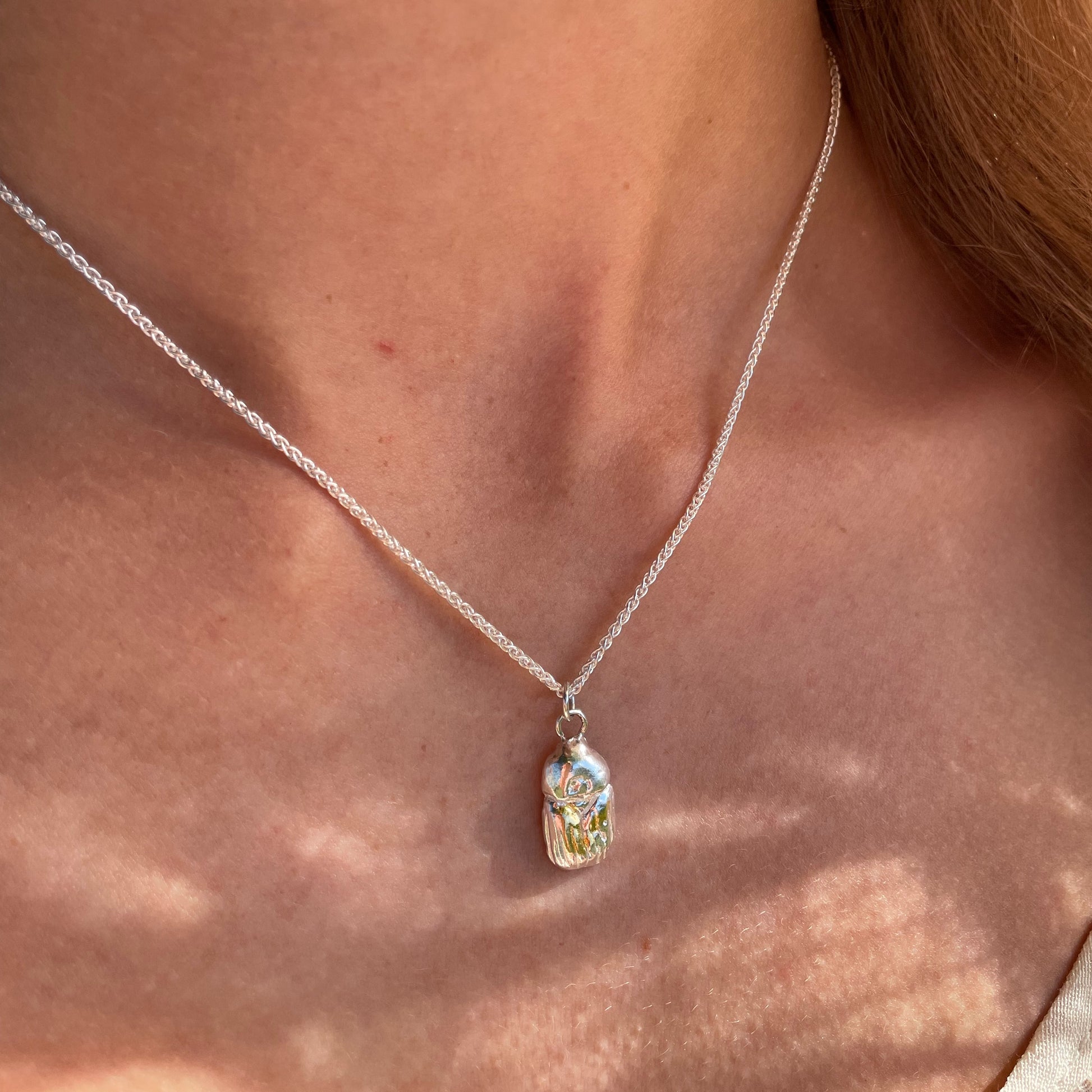The Expanded Skies Dartmoor Scarab Pendant Necklace is inspired by the Dumbledore or Dor beetle, recycled fine silver with 24ct gold accents, worn on Dartmoor.