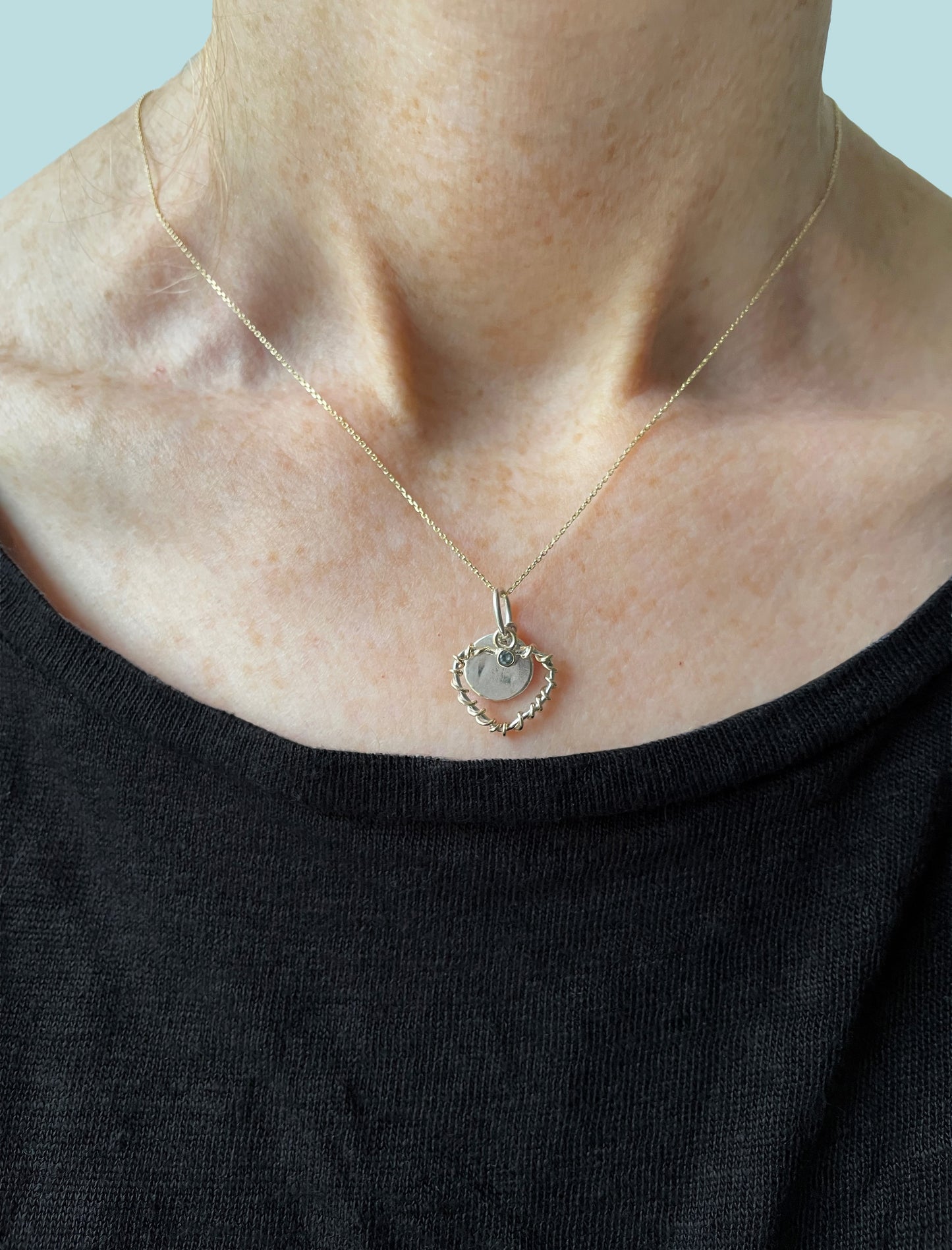 Expanded Skies Sapphire Sky Blue Heart Pendant has a beautiful ethically sourced Sri Lankan mid blue faceted sapphire set in 9ct gold on a silver heart wound with 9ct gold accompanied by a small silver disk. Totally handcrafted on the edge of Dartmoor and made from high quality recycled sterling silver and recycled gold. 