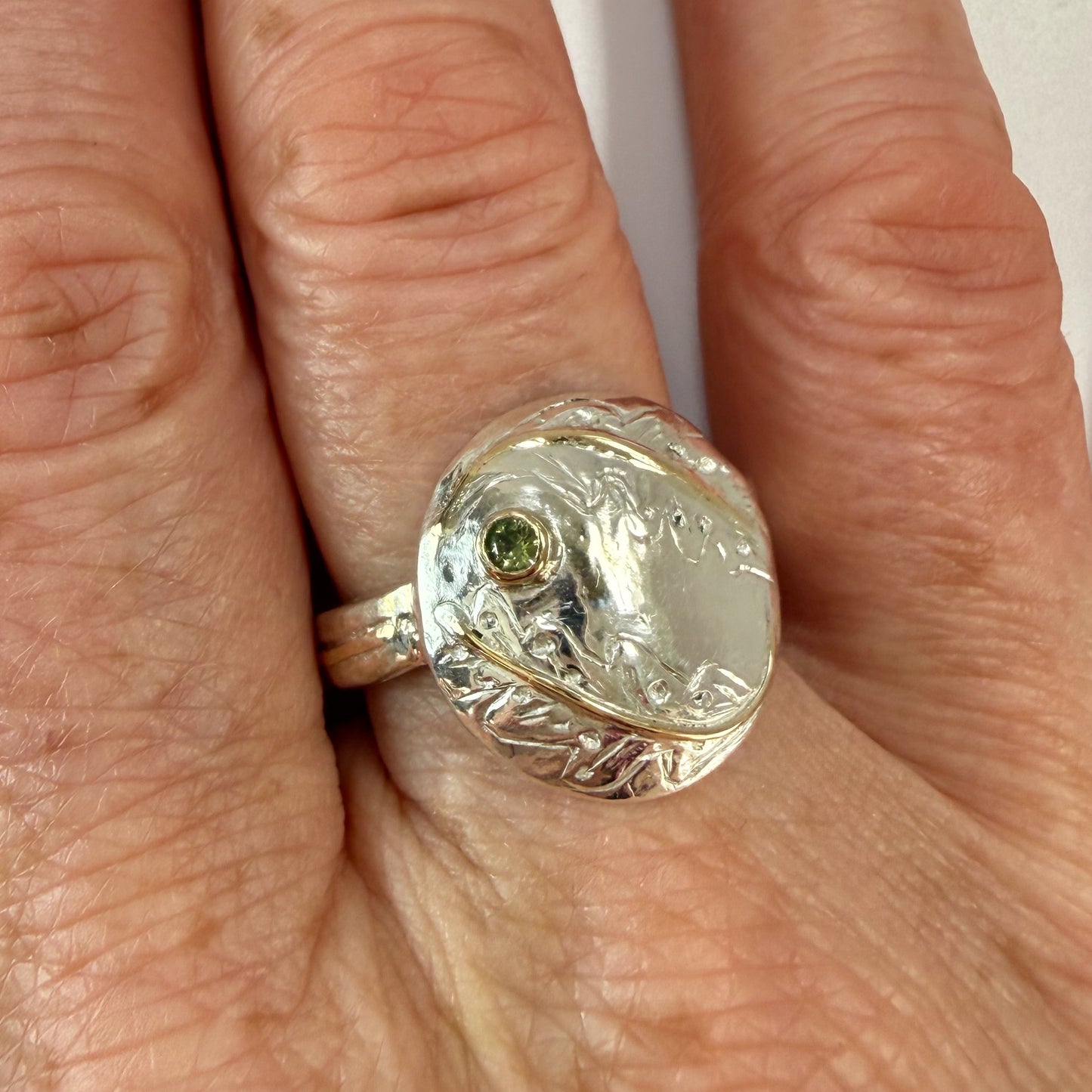 Expanded Skies Two Dartmoor Oak Leaves Sapphire Ring is inspired by the beautiful oak seedlings in Hembury Woods created in recycled sterling and fine silver, inlaid with 9ct gold with an ethically sourced Australian green sapphire set in 9ct gold, with hand engraved oak leaves.