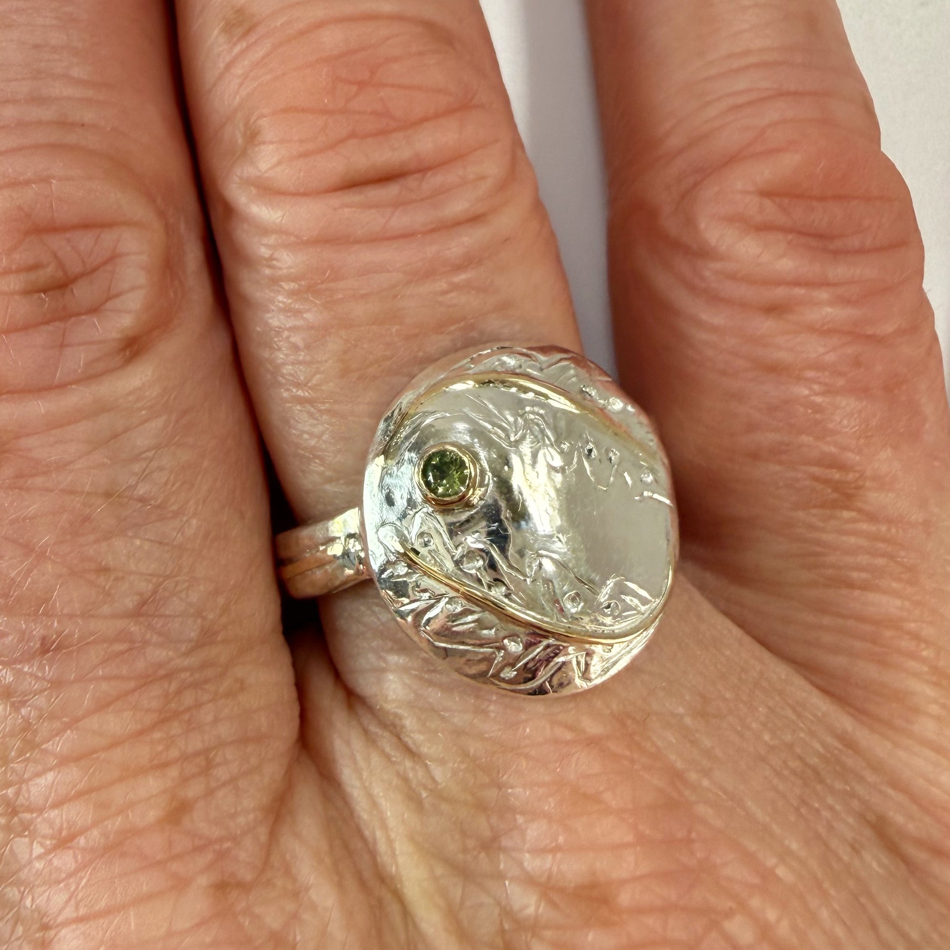 Expanded Skies Two Dartmoor Oak Leaves Sapphire Ring is inspired by the beautiful oak seedlings in Hembury Woods created in recycled sterling and fine silver, inlaid with 9ct gold with an ethically sourced Australian green sapphire set in 9ct gold, with hand engraved oak leaves.