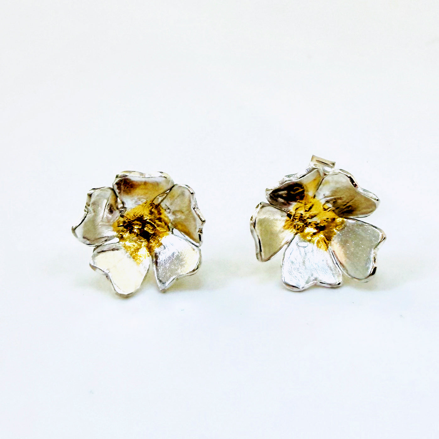 The Expanded Skies Dartmoor Field Rose Studs captures the joyous simple beauty of the field rose, Rosa arvensis, that is seen weaving brightly through the Dartmoor hedgerows and woodland.
Handcrafted in recycled fine silver with recycled 24ct gold accents and recycled sterling silver ear pins and scrolls.