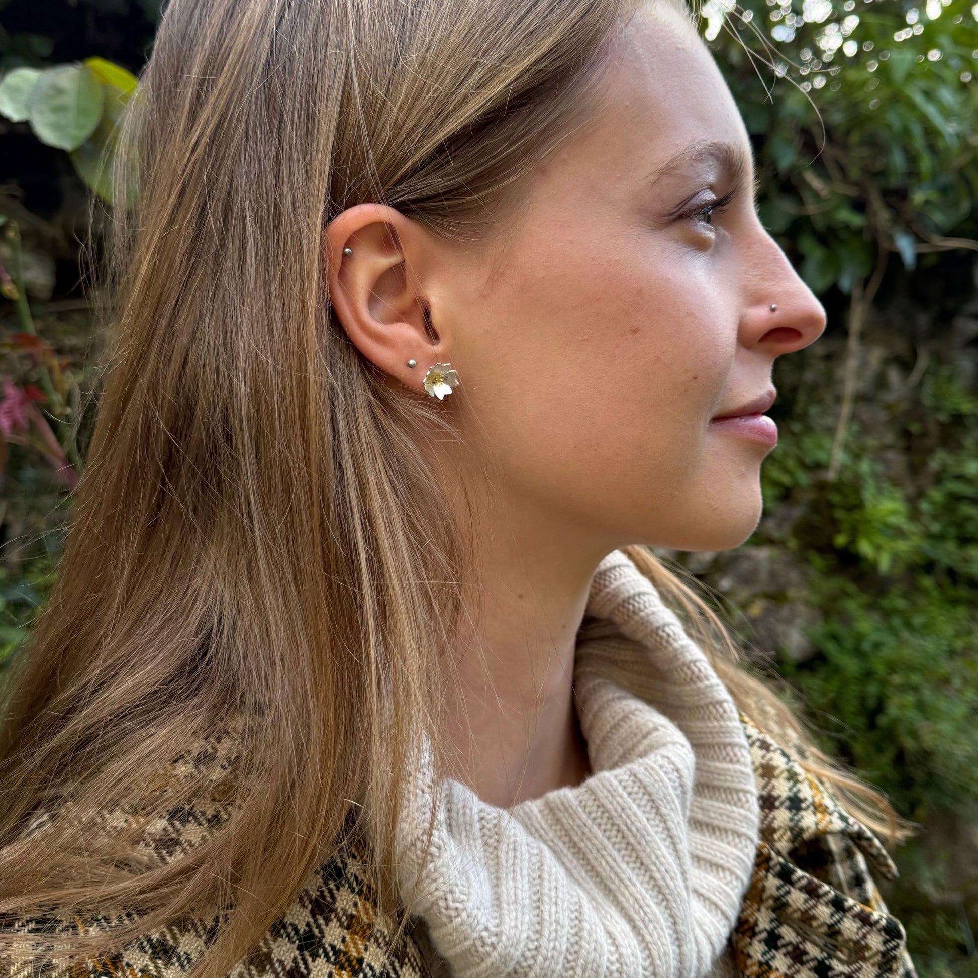 The Expanded Skies Dartmoor Field Rose Studs captures the joyous simple beauty of the field rose, Rosa arvensis, that is seen weaving brightly through the Dartmoor hedgerows and woodland.
Handcrafted in recycled fine silver with recycled 24ct gold accents and recycled sterling silver ear pins and scrolls. Worn by model.