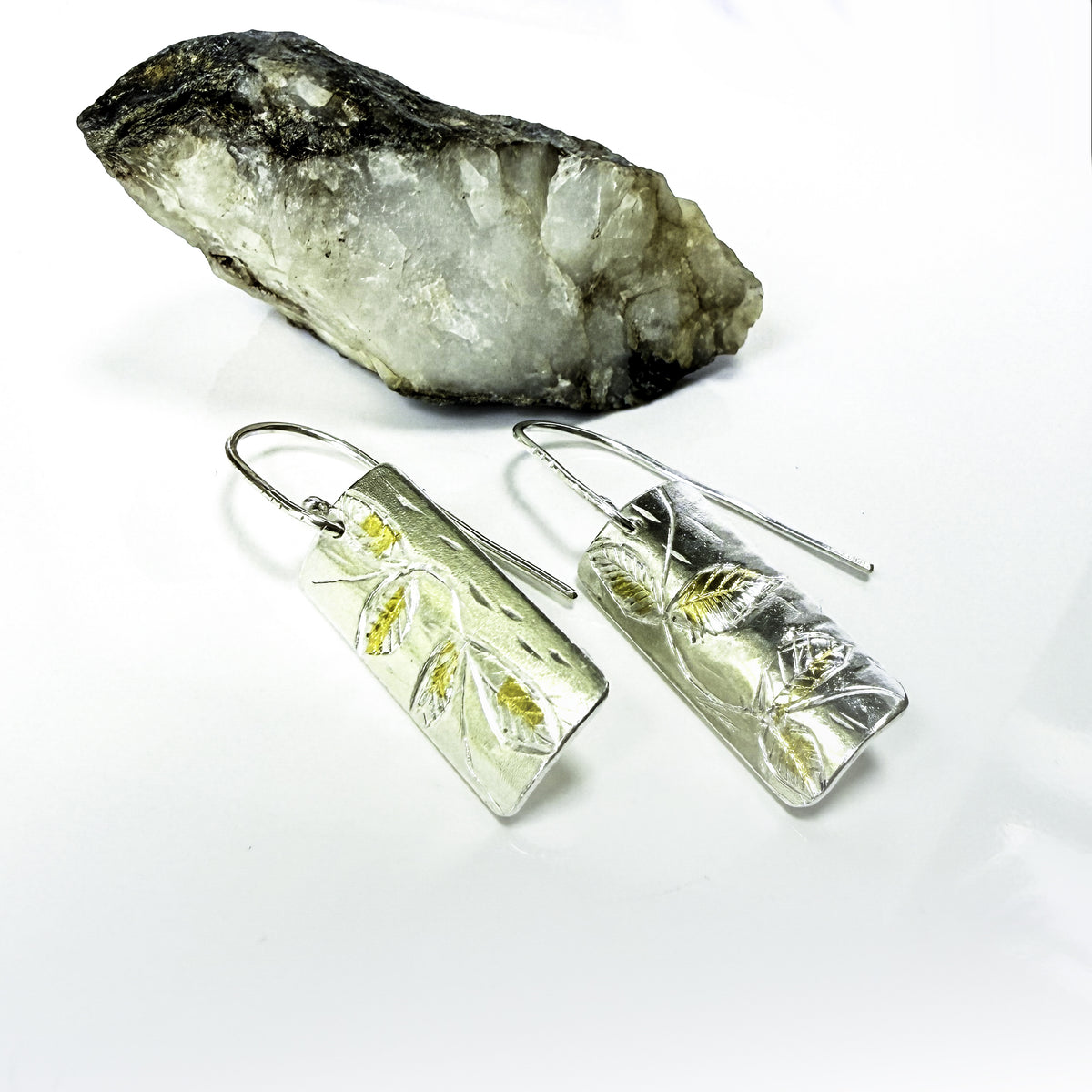 The Expanded Skies Dartmoor Honeysuckle Leaves Drop Earrings are hand engravings of the graceful honeysuckle (Lonicera periclymenum) as it winds through the trees and brambles in Ausewell Woods.

Handcrafted in recycled fine silver with recycled 24ct gold accents with sterling silver ear wires. Each earring’s hand engraving is unique. Simple and elegant with a textured, polished finish, they can be worn everyday for any occasion.

The earrings are totally handcrafted on the edge of Dartmoor and made from hi