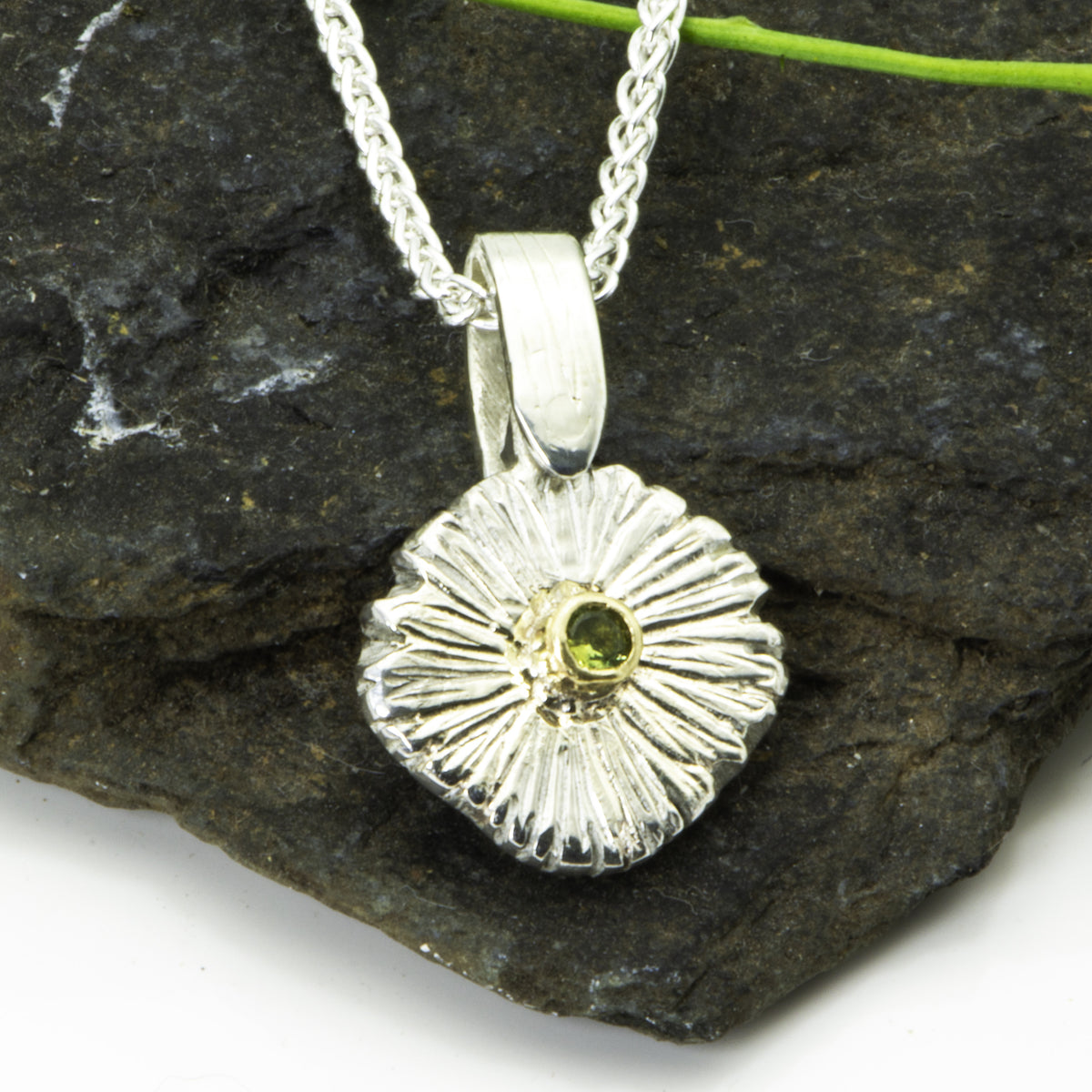 The Expanded Skies Dartmoor Green Daisy Sapphire Necklace in sterling silver and 9ct gold is inspired by the Erigeron Karvinskianus, commonly known as the 'Dartmoor Daisy'. It comes with 16” Italian spiga rolled chain, made from recycled sterling silver. The daisy pendant measures 12mm, the bail measures 6mm, total length 18mm with a depth of 2mm (approx). Each piece is individually saw pierced, hand engraved and
unique. The ethically sourced 2.5mm green sapphire is from Queensland, Australia.