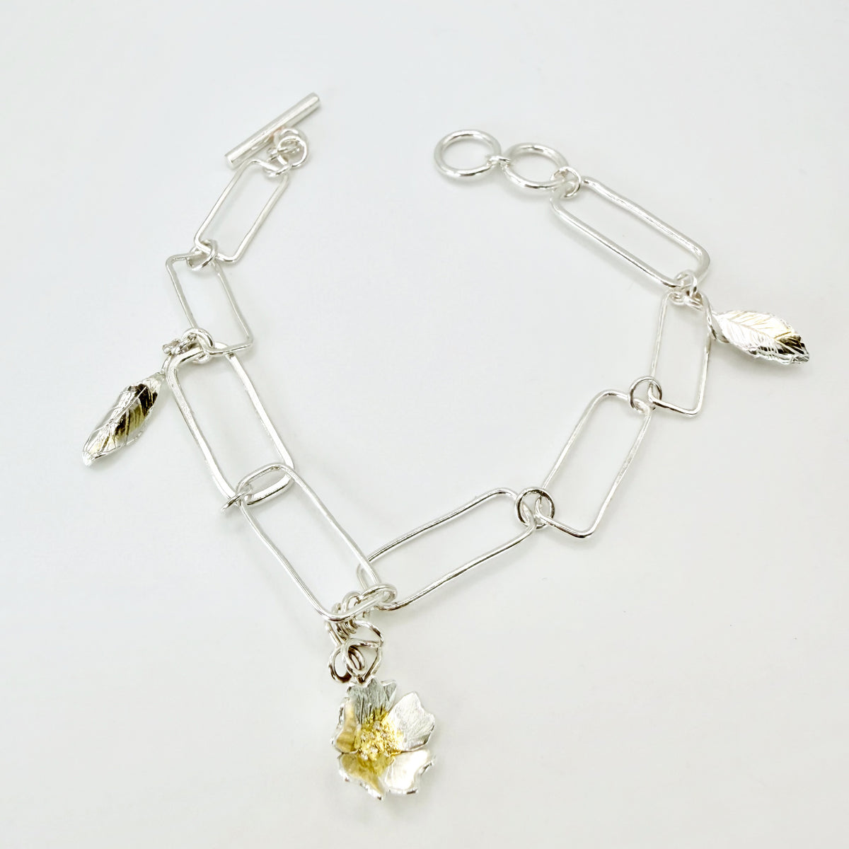 The Expanded Skies Dartmoor Field Rose Bracelet captures the joyous beauty of the field rose, Rosa arvensis, seen weaving brightly through the Dartmoor hedgerows and woodland. The bracelet’s rose and leaves are hand engraved and has a painterly feel, accented with 24ct gold.