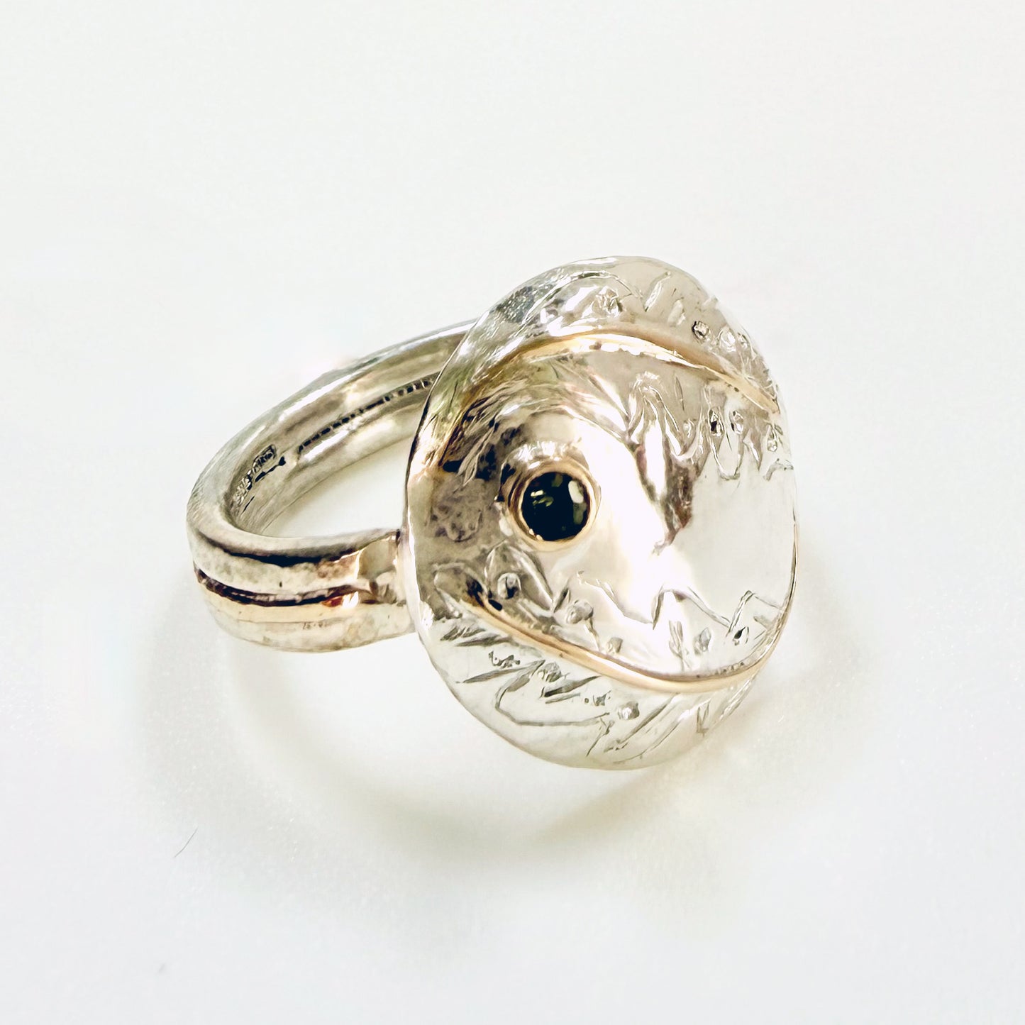 Expanded Skies Two Dartmoor Oak Leaves Sapphire Ring is inspired by the beautiful oak seedlings in Hembury Woods created in recycled sterling and fine silver, inlaid with 9ct gold with an ethically sourced Australian green sapphire set in 9ct gold, with hand engraved oak leaves.