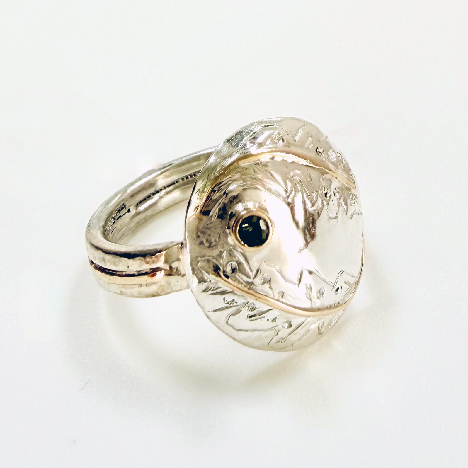 Expanded Skies Two Dartmoor Oak Leaves Sapphire Ring is inspired by the beautiful oak seedlings in Hembury Woods created in recycled sterling and fine silver, inlaid with 9ct gold with an ethically sourced Australian green sapphire set in 9ct gold, with hand engraved oak leaves.