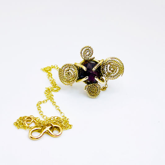 The Expanded Skies Raw Garnet Spiral Filigree Necklace has a beautiful raw Norwegian garnet set in 9ct gold. The garnet is set in a distinctive completely handcrafted 9ct gold filigree and claw setting. It features the neolithic symbol of the spiral, representing the life force and the cycles of life. This is a unique piece, one-of-a-kind. Handcrafted on the edge of Dartmoor and made from high quality recycled gold, Hallmarked by the London Assay Office.
