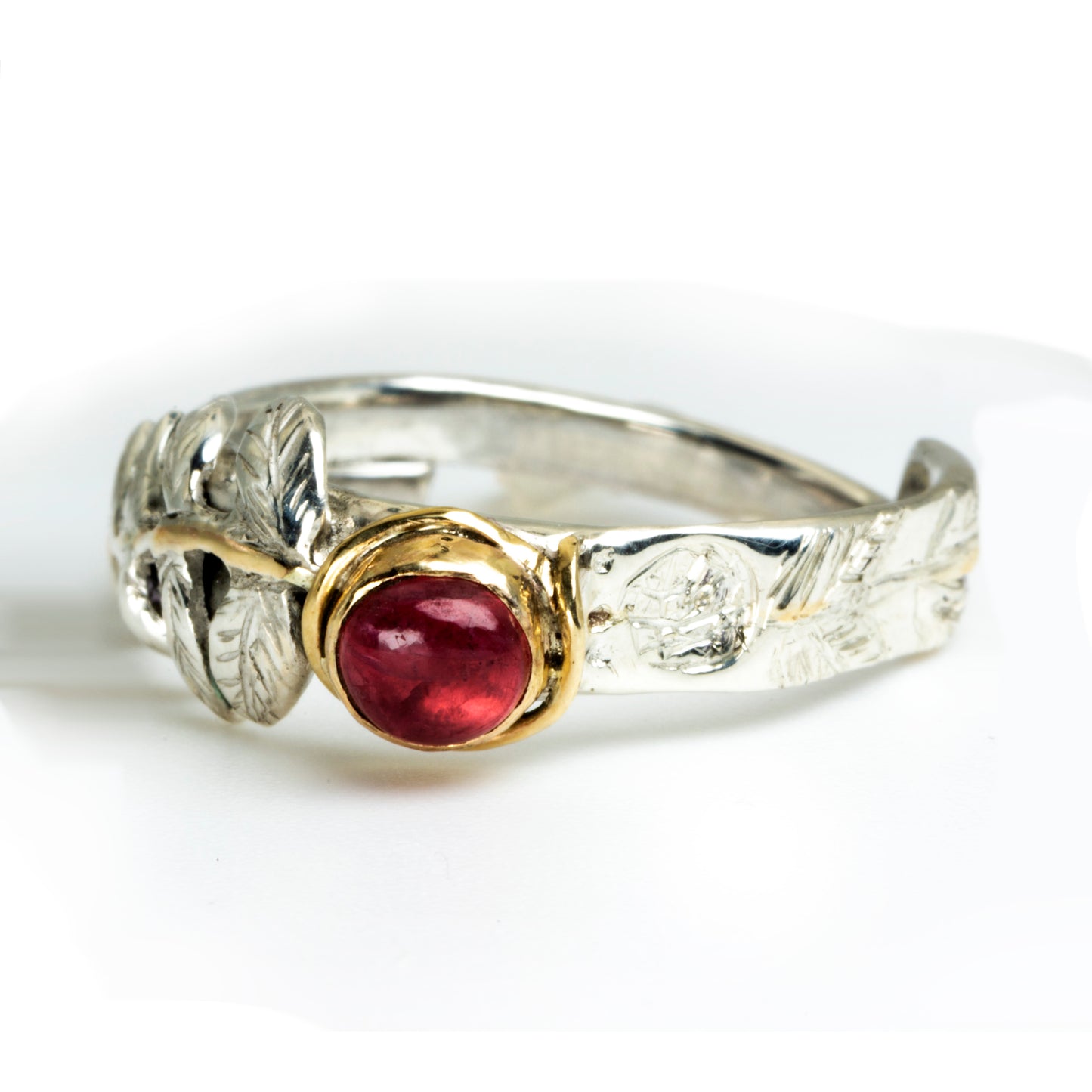 
Expanded Skies Dartmoor Rowan Leaf and Berries Spinel Ring. The Expanded Skies Dartmoor Rowan Leaf and Berries Spinel Ring is totally handcrafted on the edge of Dartmoor. The ring is created in recycled sterling silver, inlaid with 9ct gold. The ring is set with an ethically sourced Tanzanian red-pink spinel, set in 9ct gold, with a hand formed rowan leaf, inlaid with 9ct gold. The ethically sourced 4.5mm round spinel is from Moyo Gems. Moyo gems is run by female miners Tanzanian Women Miners' Association.