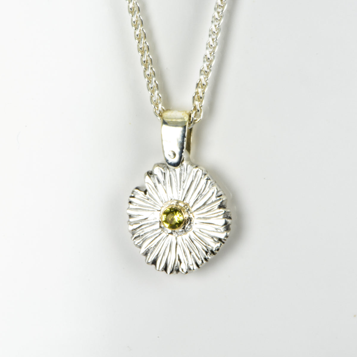 The Expanded Skies Dartmoor Daisy Sapphire Necklace in sterling silver and 9ct gold is inspired by the Erigeron Karvinskianus, commonly known as the 'Dartmoor Daisy'. It comes with 16” Italian spiga rolled chain, made from recycled sterling silver. The daisy pendant measures 12mm, the bail measures 6mm, total length 18mm with a depth of 2mm (approx). Each piece is individually saw pierced, hand engraved and
unique. The ethically sourced 2.5mm yellow sapphire is from Queensland, Australia.