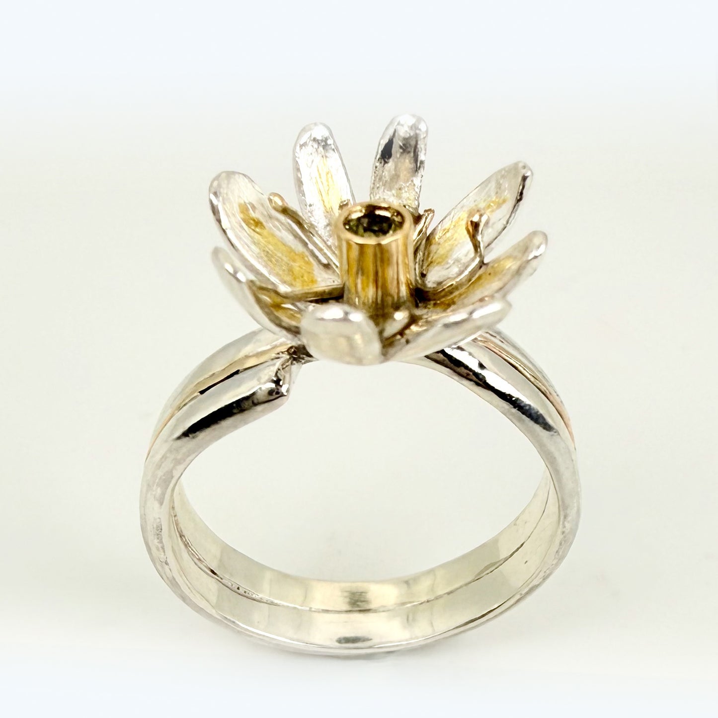 Expanded Skies Dartmoor Celandine Sapphire Ring celebrates the beauty of the waysides and meadows, radiant with wild yellow celandines (Ficaria verna).

The ring is totally handcrafted on the edge of Dartmoor. The band is made from sterling silver, inlaid on the shoulders with 9ct gold.

The flower is made from fine silver with 24ct gold accents fused to the surface of the petals. The celandine has a 9ct gold setting for the beautiful ethically sourced yellow-green sapphire, that really captures the colours